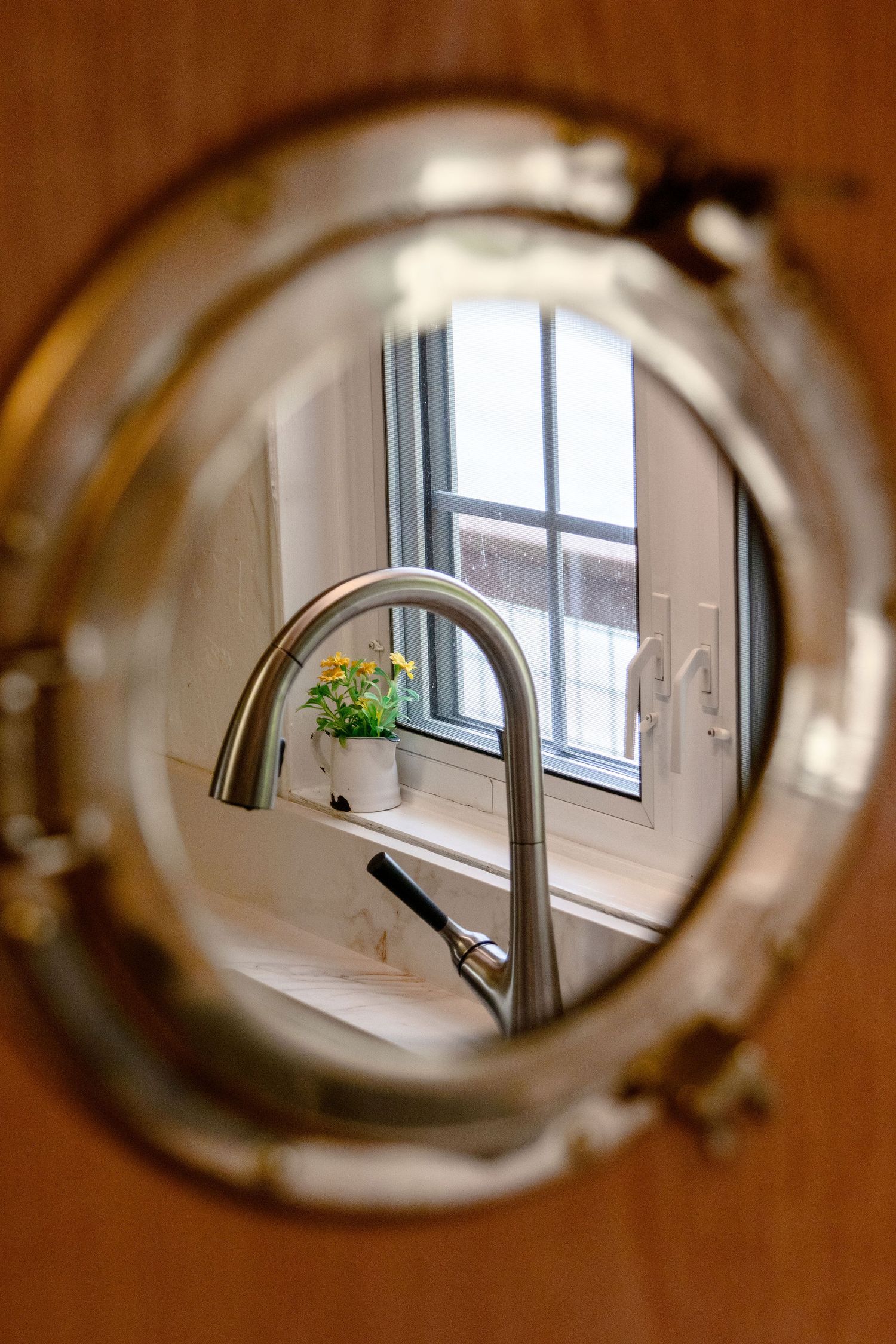Artistic fisheye view through window showing modern kitchen faucet and sink installation.