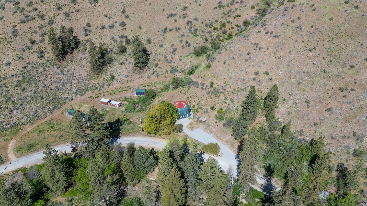 Aerial view of desert hillside with scattered vegetation and dirt roads cutting through terrain.