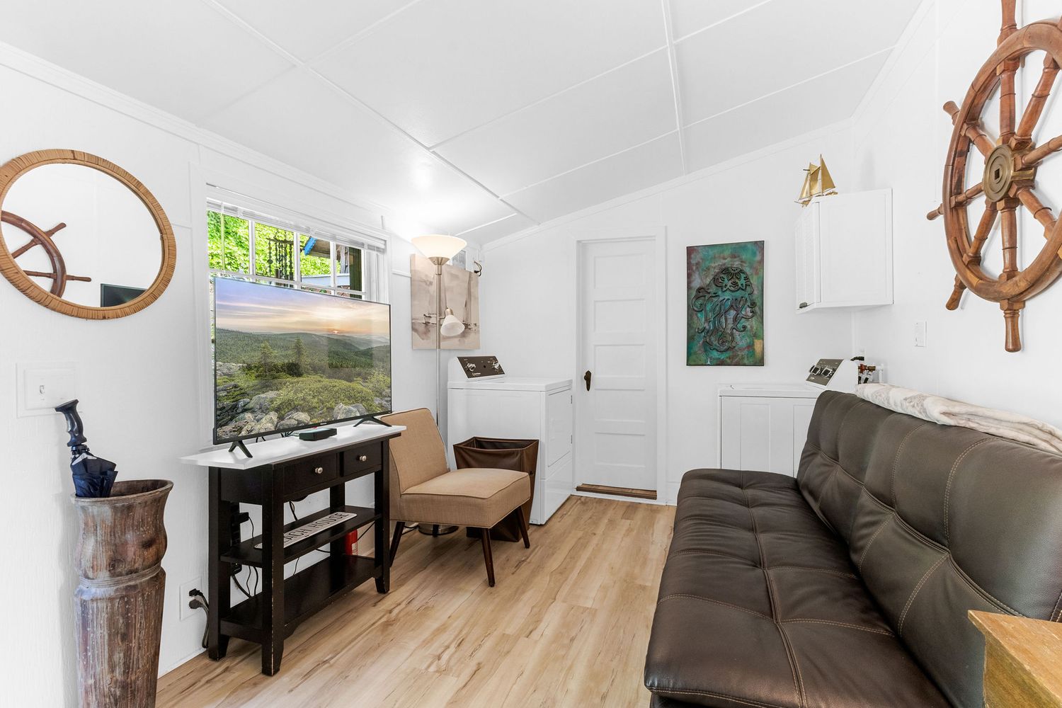 Beach house living area decorated with nautical elements including ship wheels and coastal artwork.