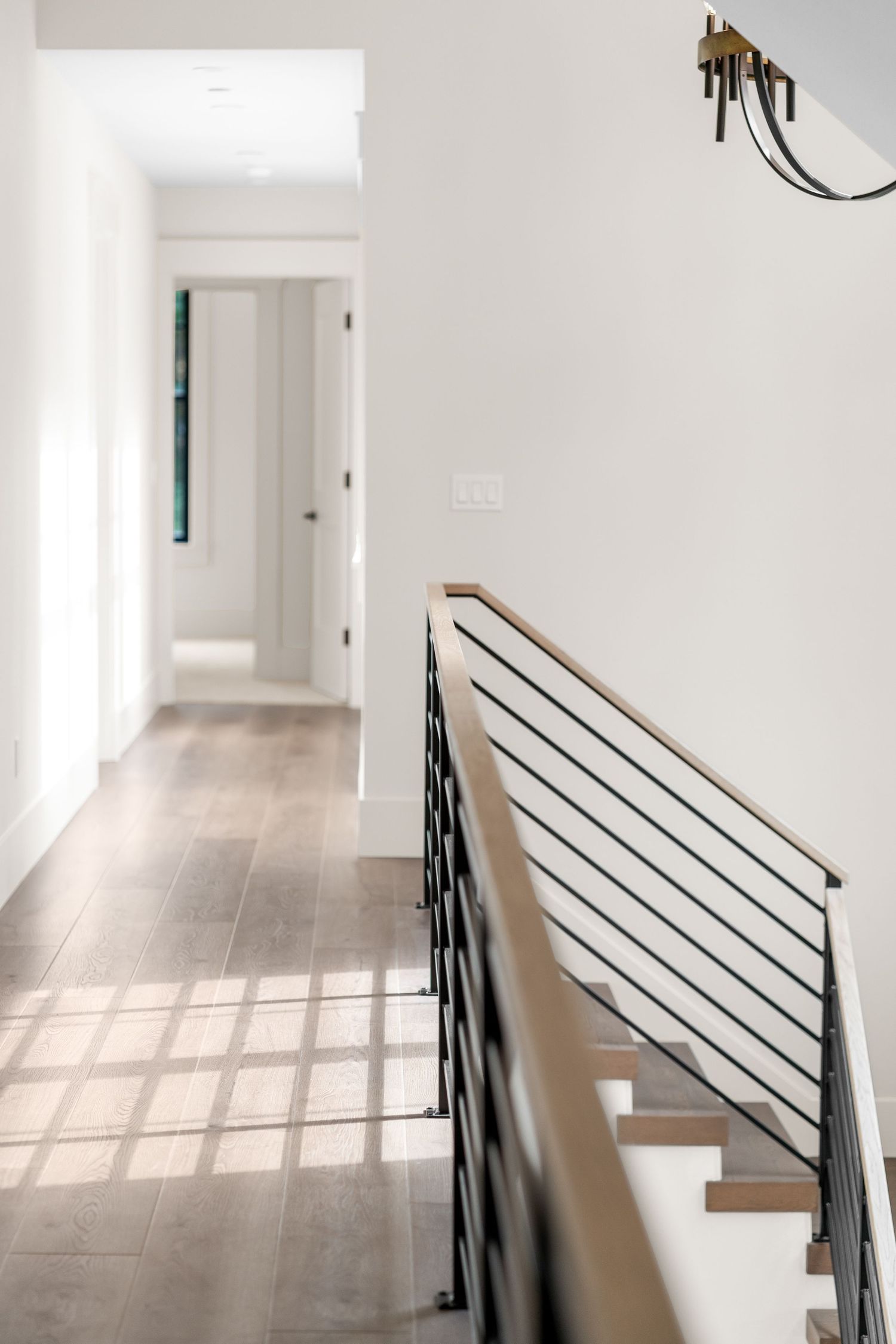 Minimalist hallway with metal railings showcases natural light streaming through windows.