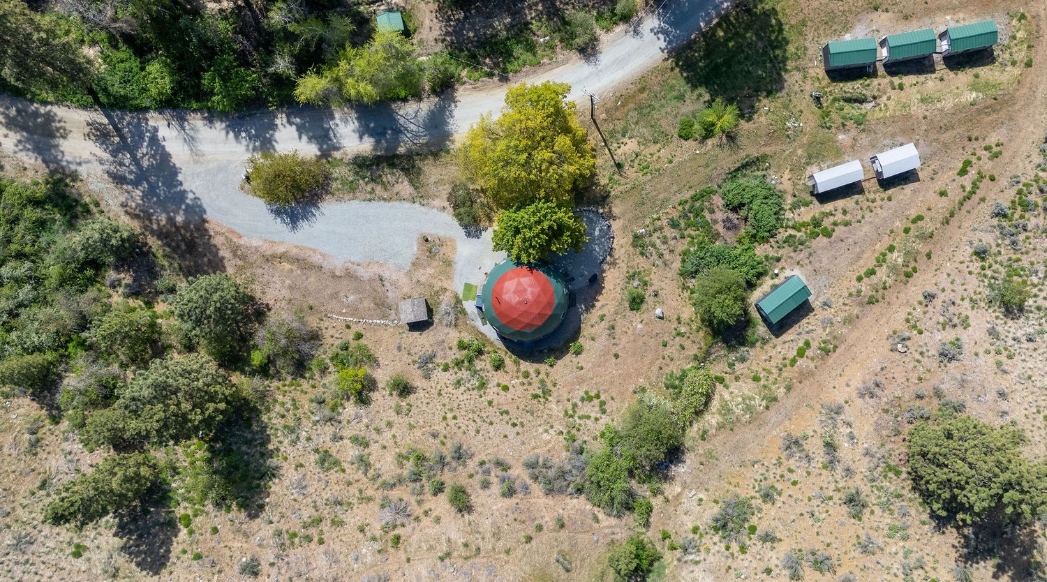 Aerial view of scattered camping trailers and vehicles on mountainside terrain.