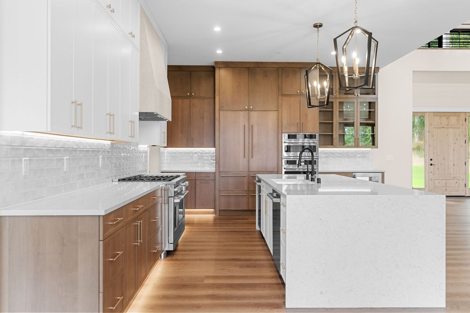 Modern white kitchen with waterfall island countertop and sleek cabinetry.