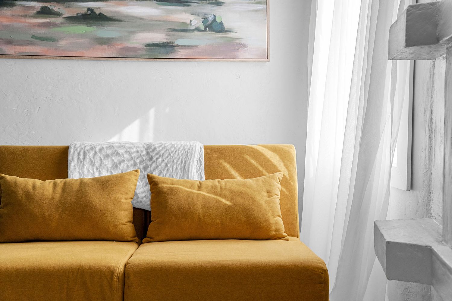Minimalist living space featuring a golden leather couch against white walls with artwork.