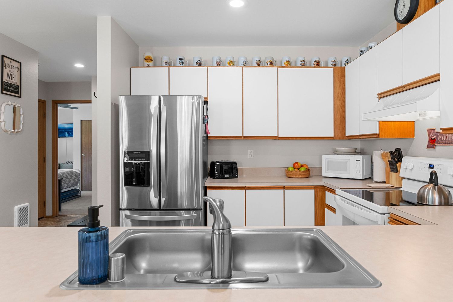 Spacious white kitchen with stainless steel appliances and orange accent trim.