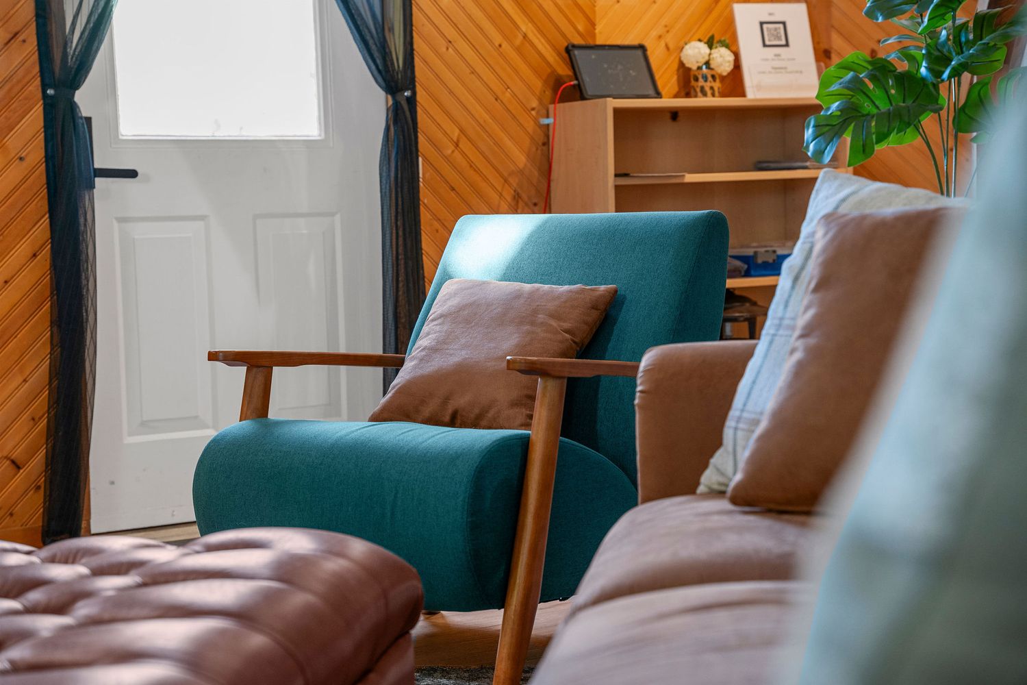 Cozy sitting area with teal armchairs and wooden paneled walls.