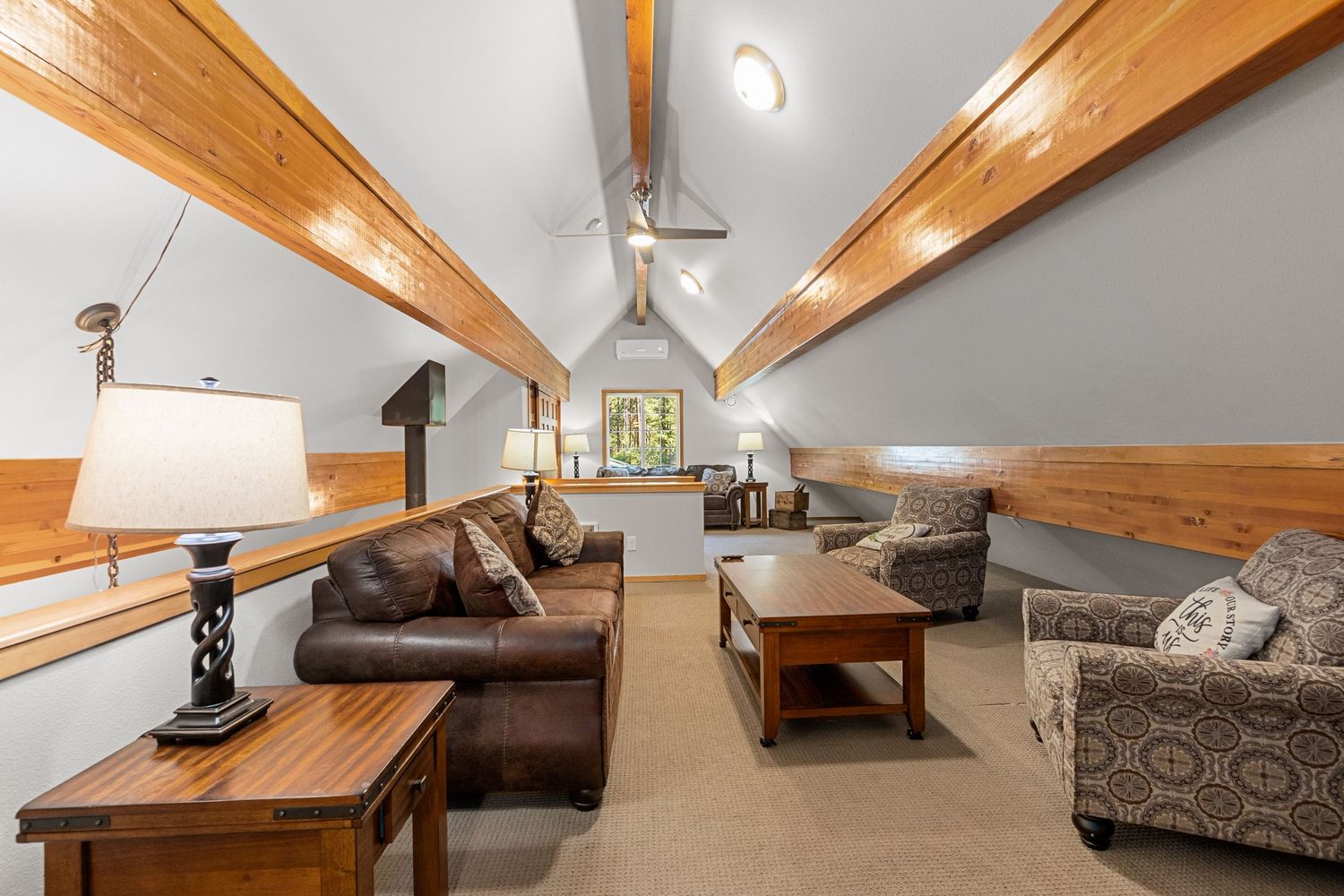 Open concept living space with exposed wooden beams and comfortable seating arrangements.
