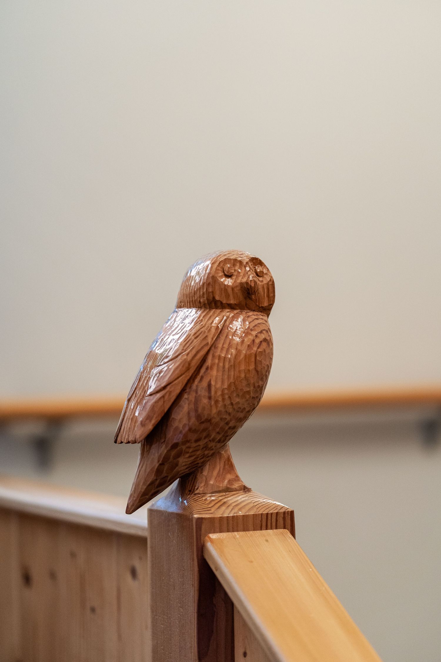 Series of carved wooden owl decorations perched on a wooden banister or railing.