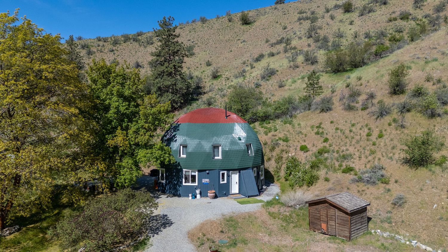 Rustic blue house nestled in scenic hillside surrounded by natural landscape.