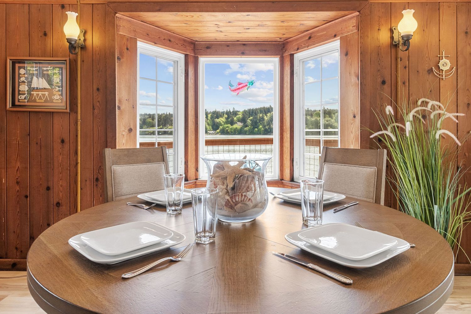 Rustic wood-paneled dining area with table settings and built-in windows showcasing water views.