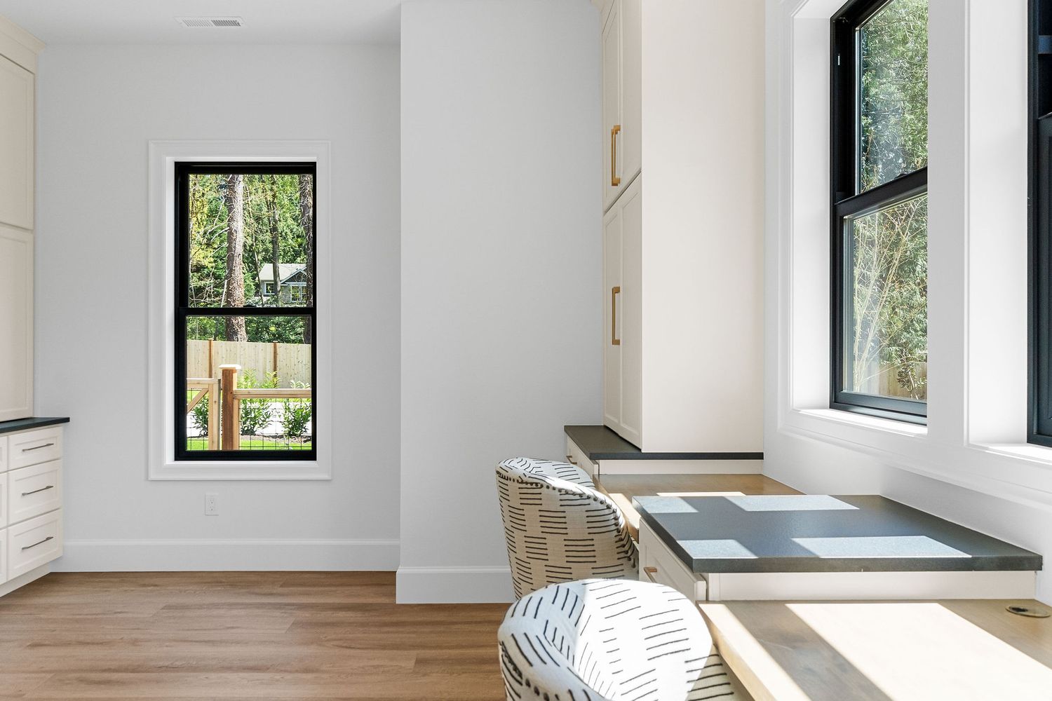 Minimalist white room with window seat and black-framed windows bringing in natural light.