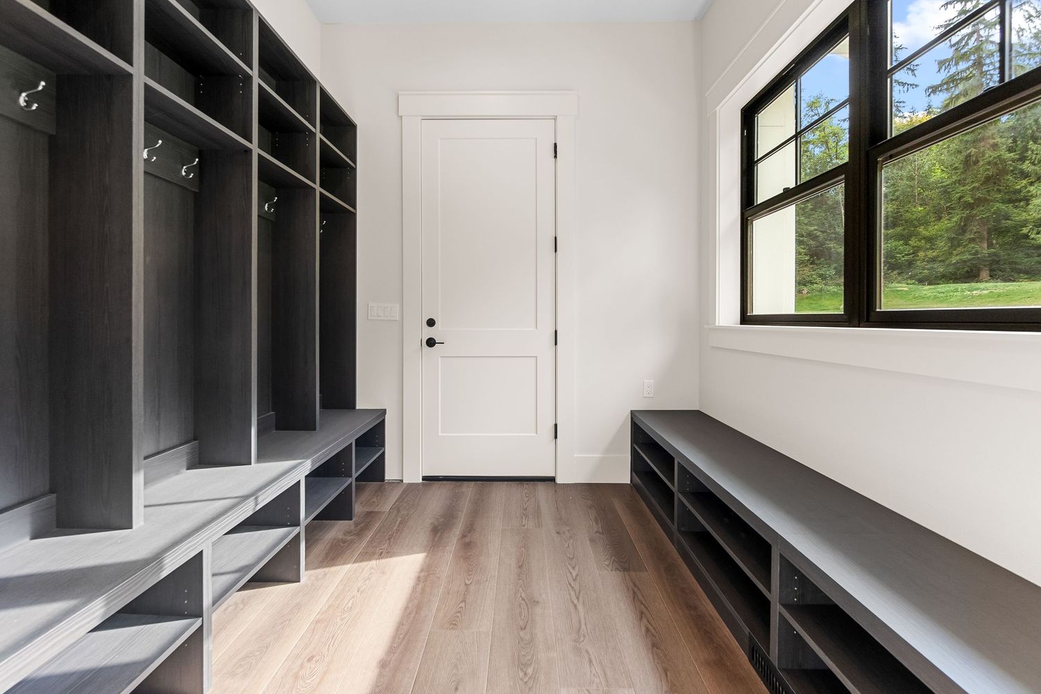 Built-in black storage shelving unit spanning the length of a modern hallway.
