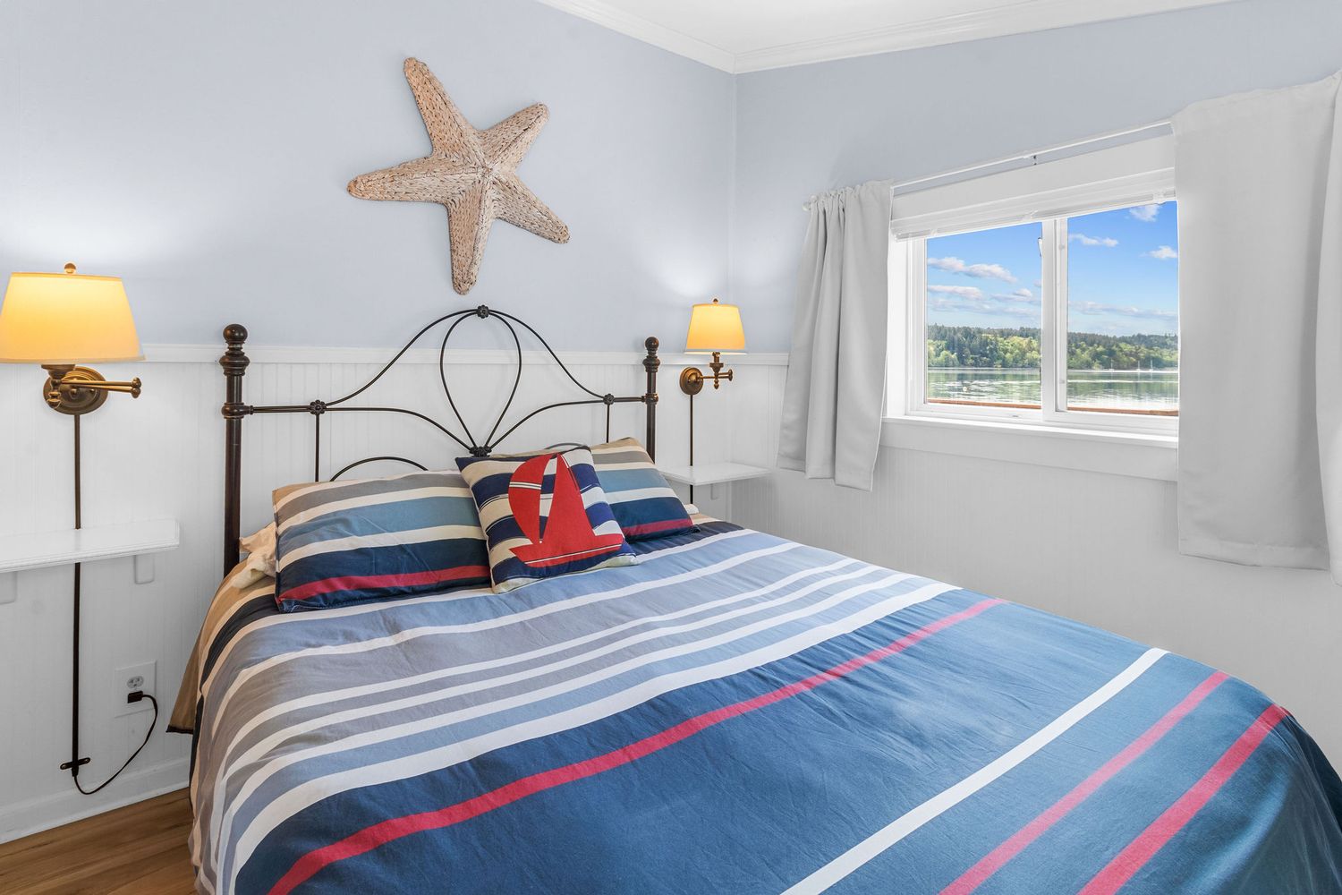 Nautical-themed bedroom with blue and white striped bedding, starfish decor, and waterfront views.