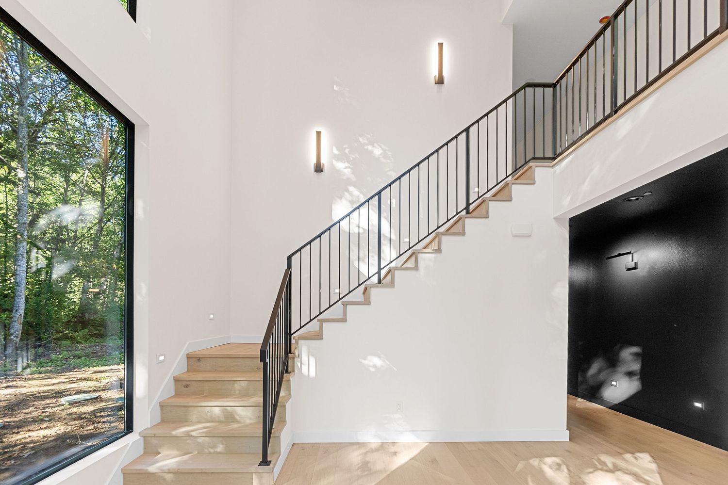 Modern staircase with metal railings and wooden steps leading upstairs in bright interior space.