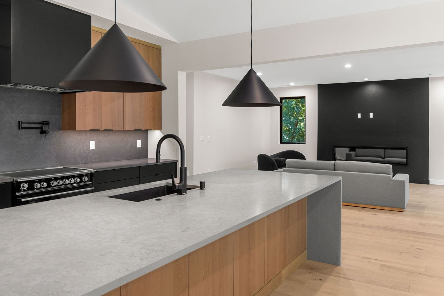 Modern kitchen featuring wood cabinets, pendant lights, and sleek countertops in an open layout design.