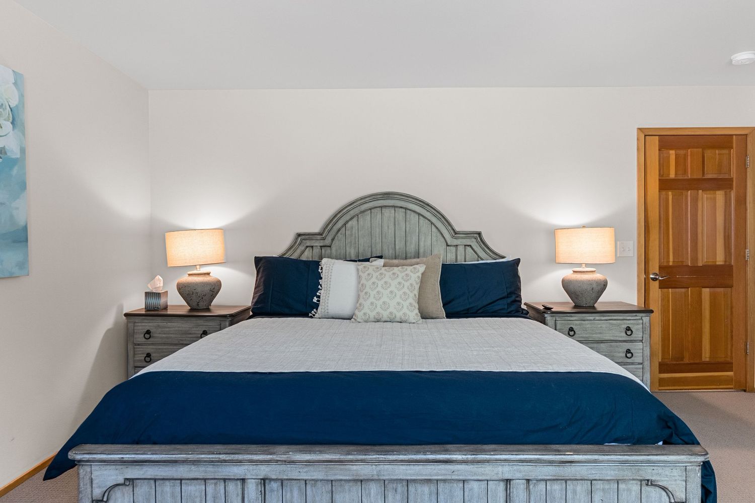 Cozy bedroom interior showcasing modern decor with blue bedding, rustic wooden furniture, and warm ambient lighting.
