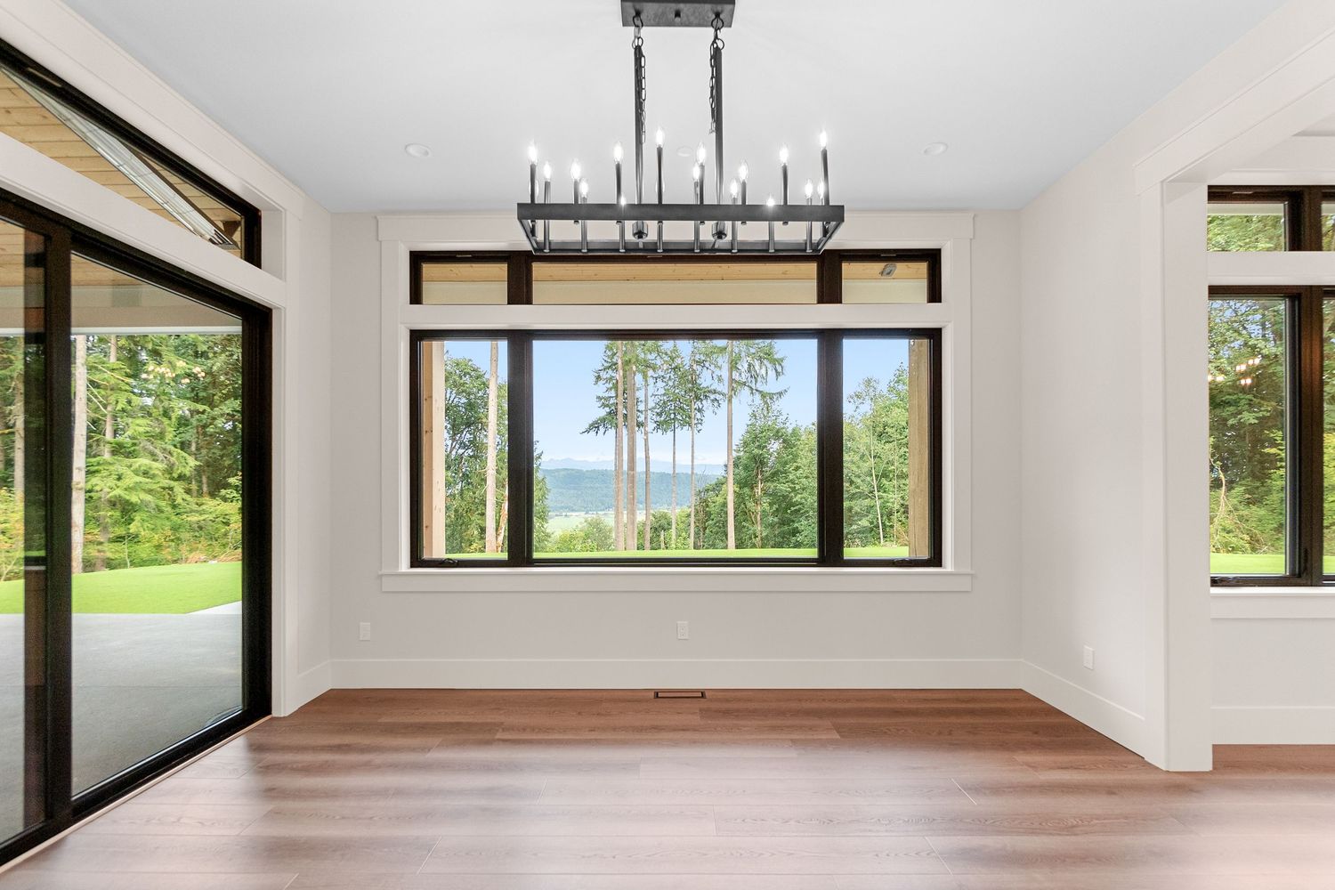 Spacious open concept living area with white walls and large windows bringing in natural light.