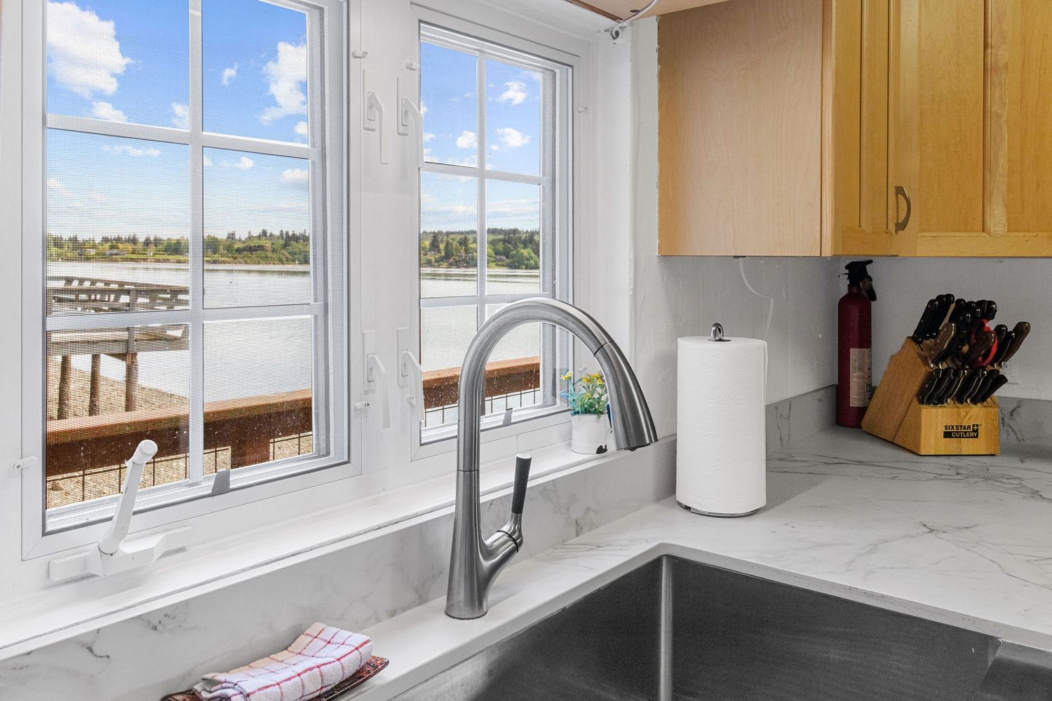 Bright kitchen windows frame stunning waterfront views in this modern coastal home.