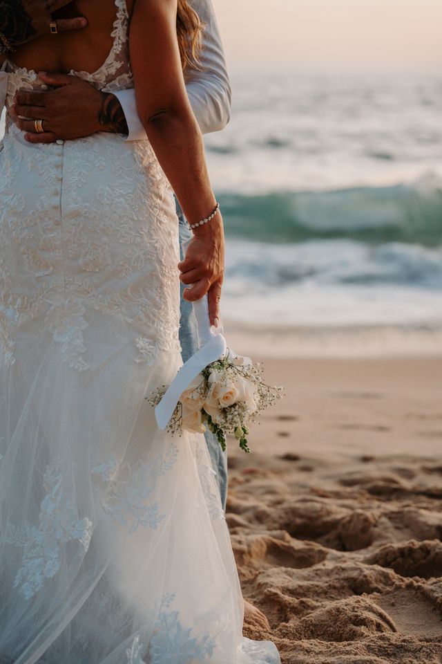 Engagement photo of a bride on a beach during sunset holding a bouquet of flowers