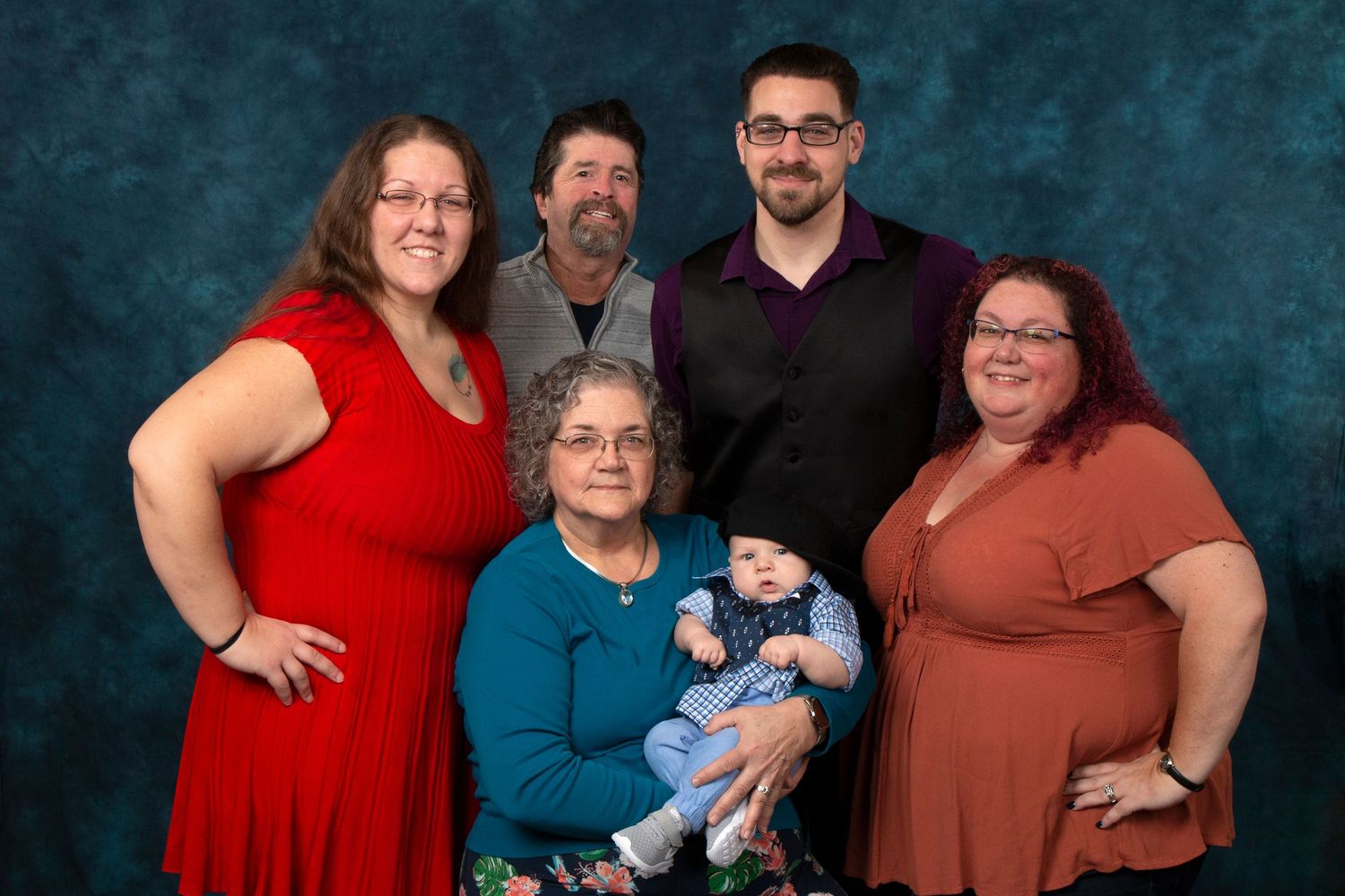 Multi-generational family portrait with grandmother holding newborn baby surrounded by adult children.