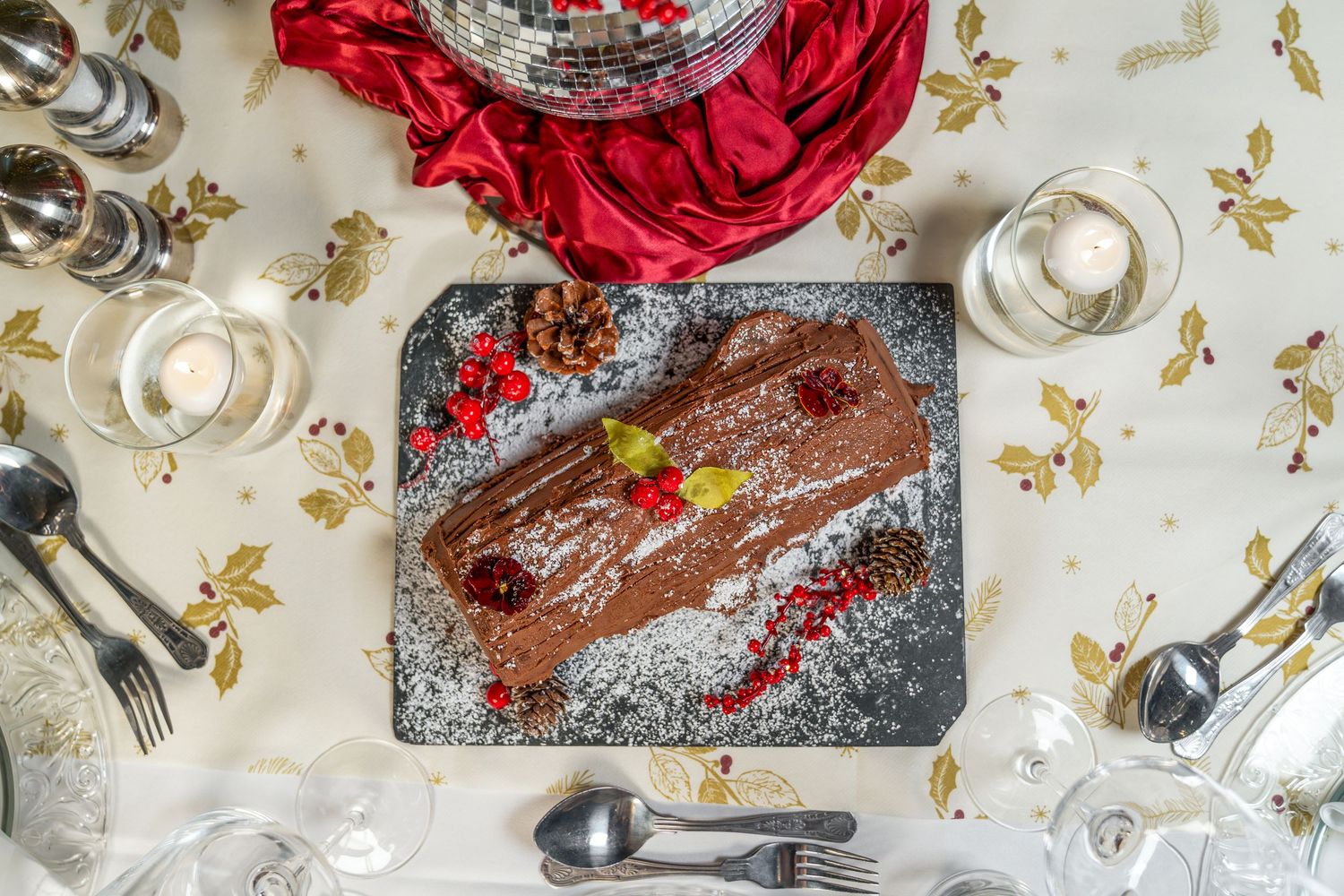 Vibrant red roses and silver decorative elements create an elegant holiday table setting with sparkling ornaments.