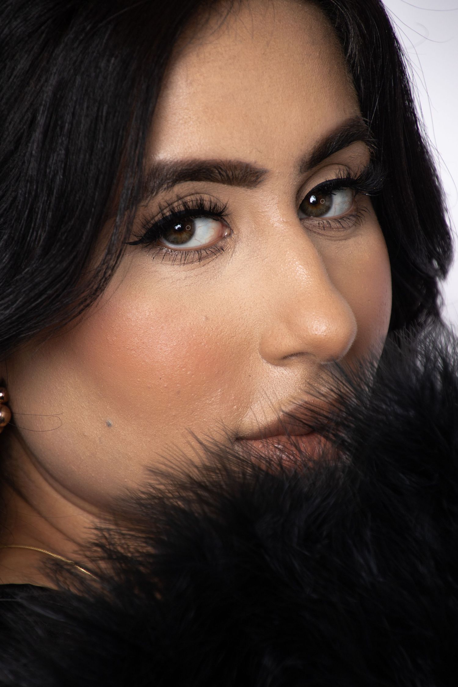 Close-up beauty portrait with dramatic lighting showcasing dark hair and glamorous makeup.