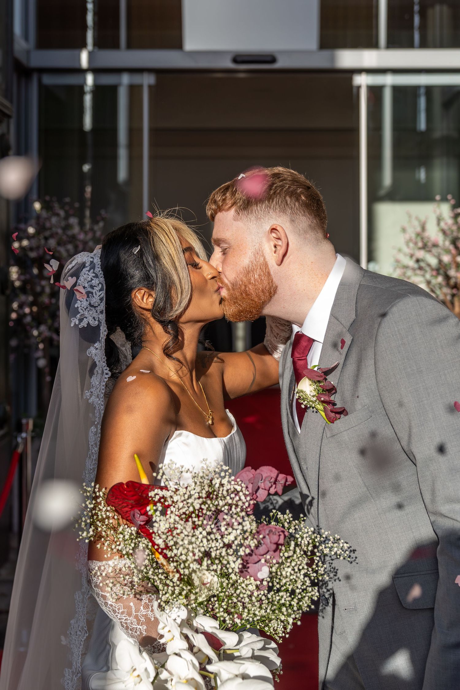 A couple shares a romantic kiss at their wedding ceremony with baby's breath flowers in the foreground.