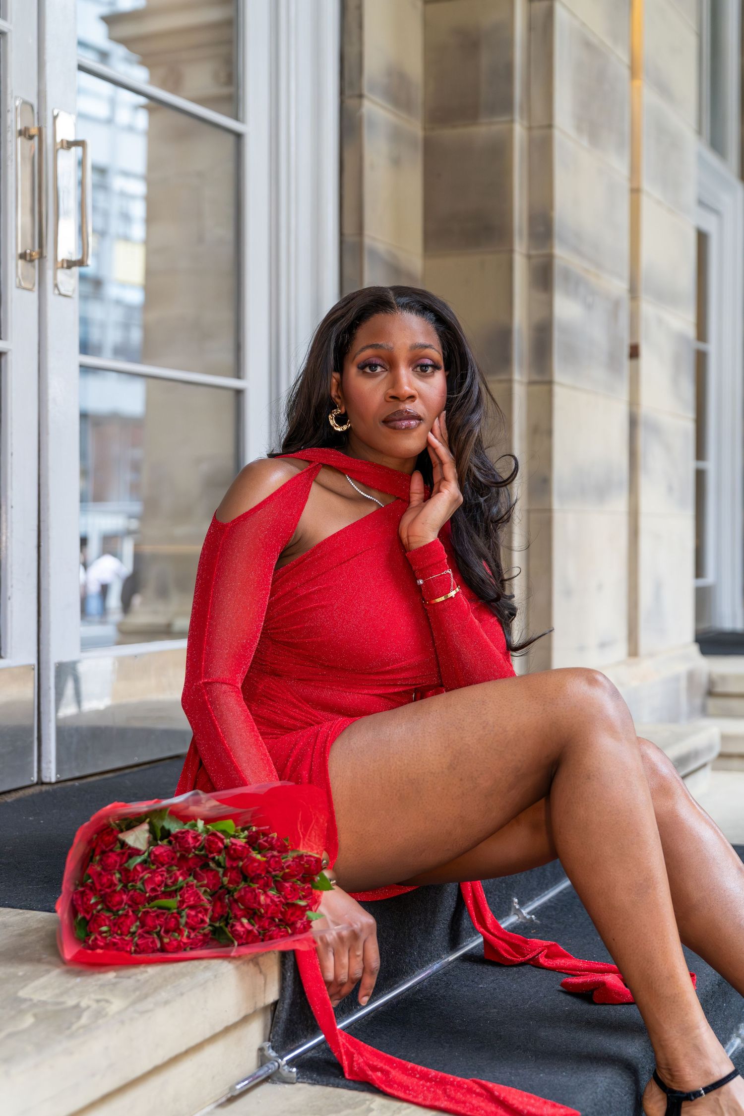 Red dress and roses create romantic Valentine's Day themed fashion scene.