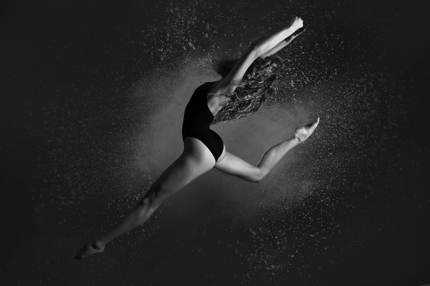Silhouetted figures gracefully dive and swim underwater in a dramatic black and white artistic composition.