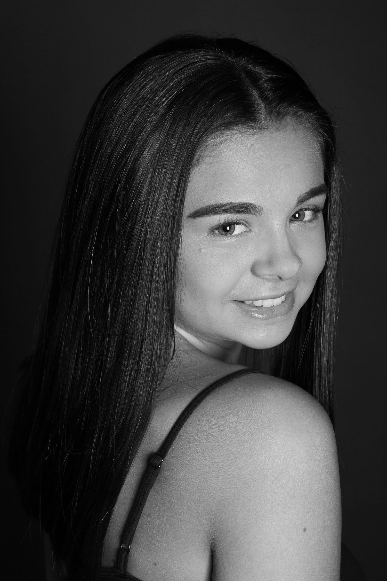 Black and white portrait of a young person with long straight dark hair and a gentle smile.