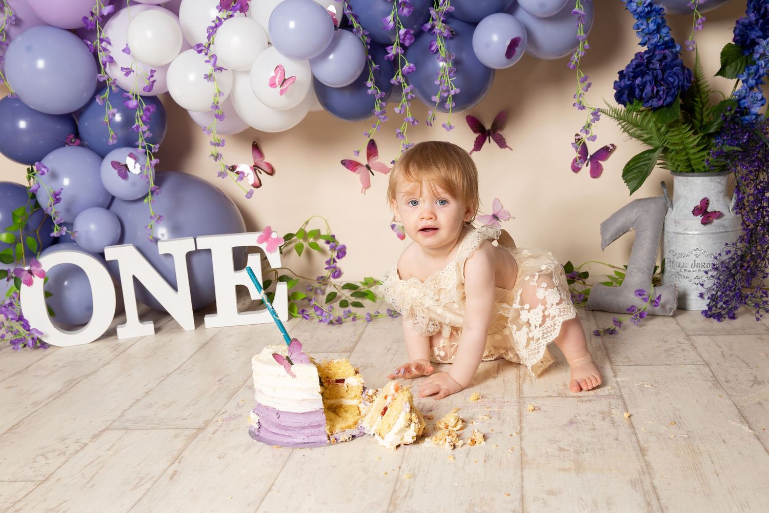 Decorative purple and grey balloon arch backdrop with flowers creates an elegant celebration setting.
