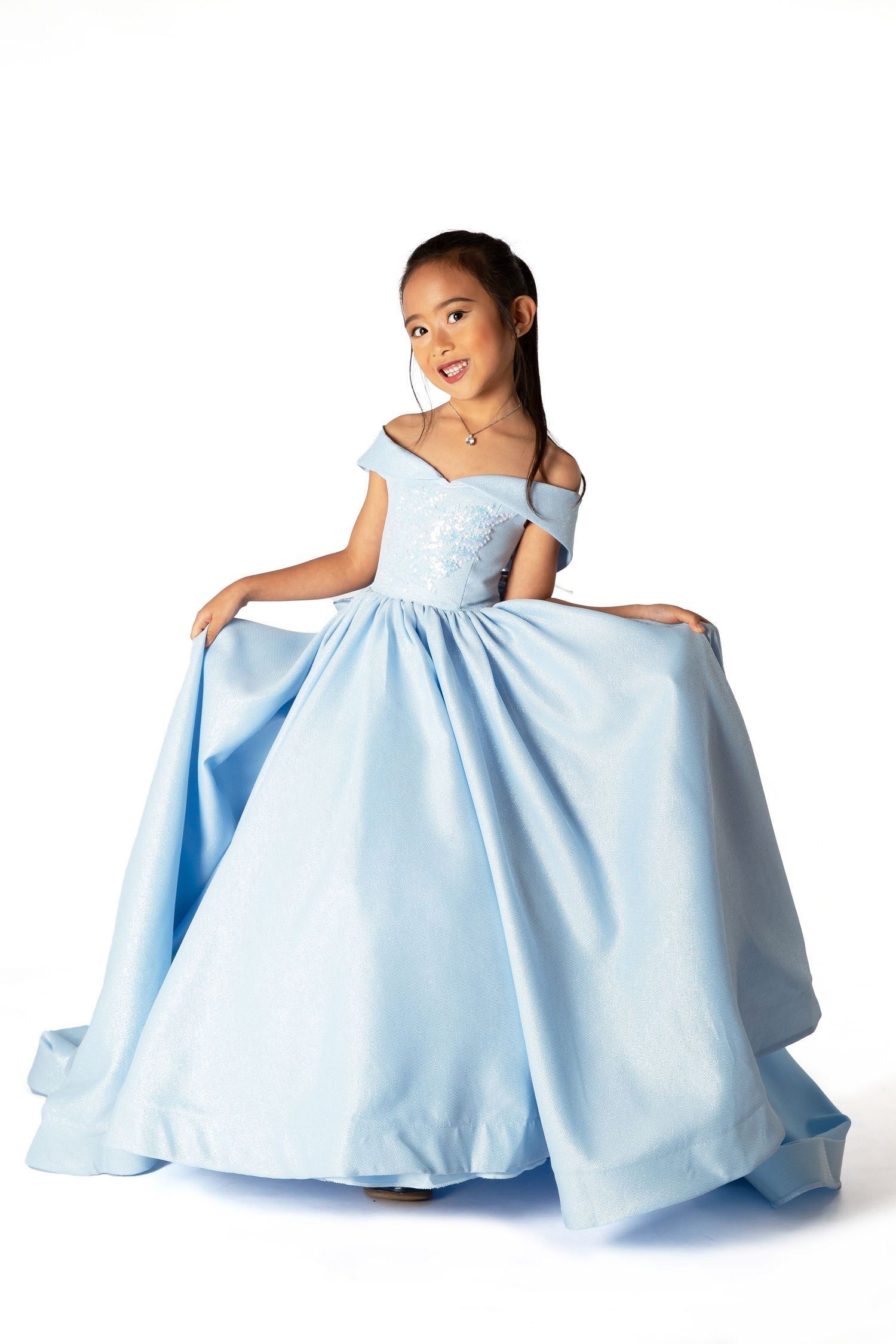 A happy young dancer in an elegant light blue ball gown twirls and poses gracefully in multiple captured movements.