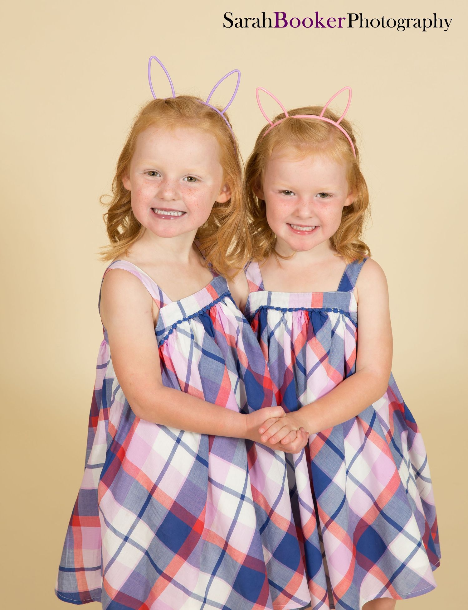 Two young children in matching plaid dresses pose and play together in a series of four playful portraits.