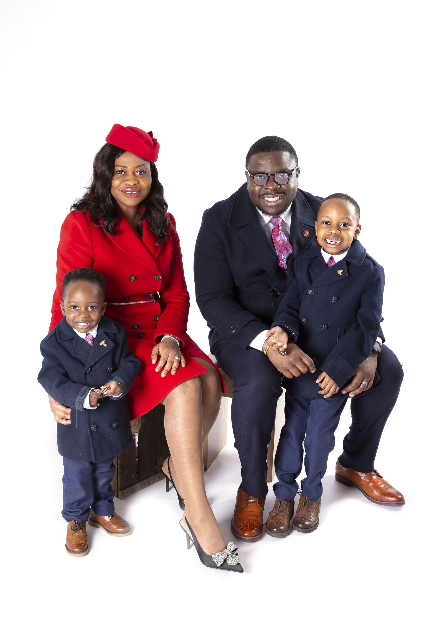 A family wearing navy blazers and dress clothes sits and crouches in progressive poses against a white background.