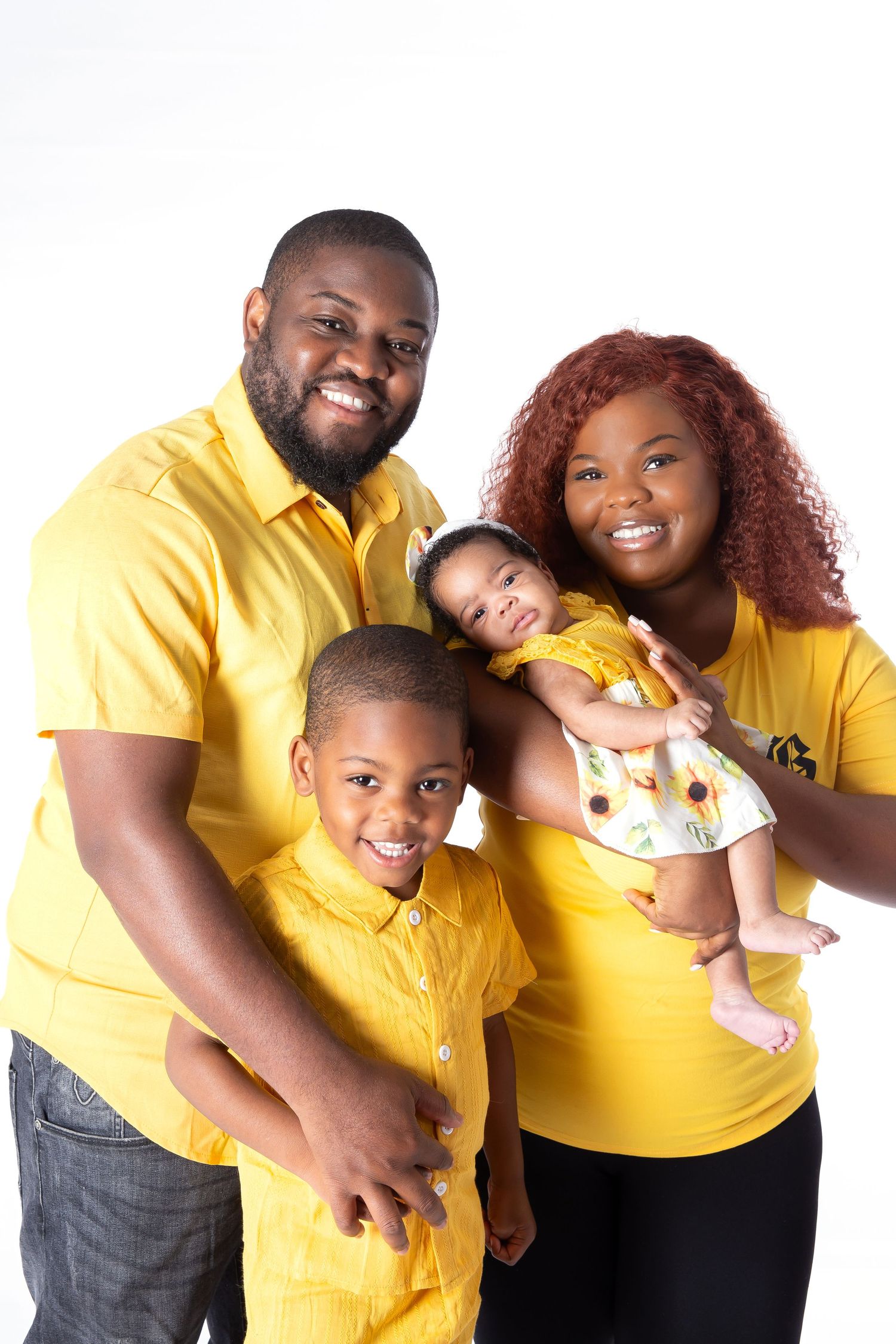 Family wearing matching yellow shirts poses together against white background for a heartwarming portrait.