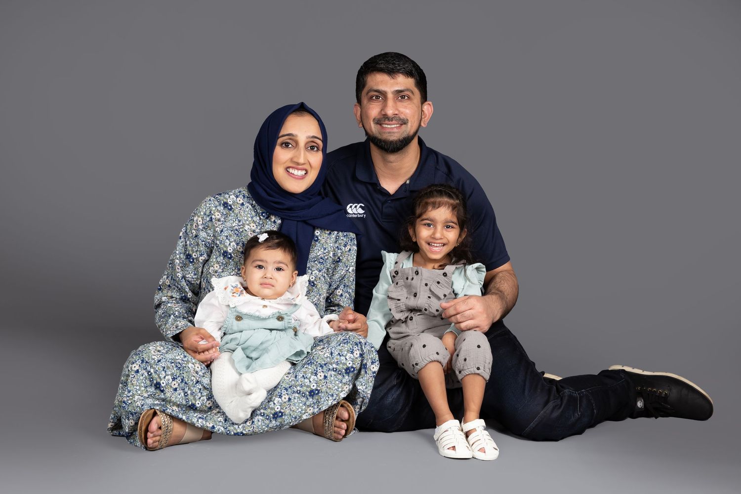 Family wearing blue and white outfits poses together for a casual studio photoshoot.