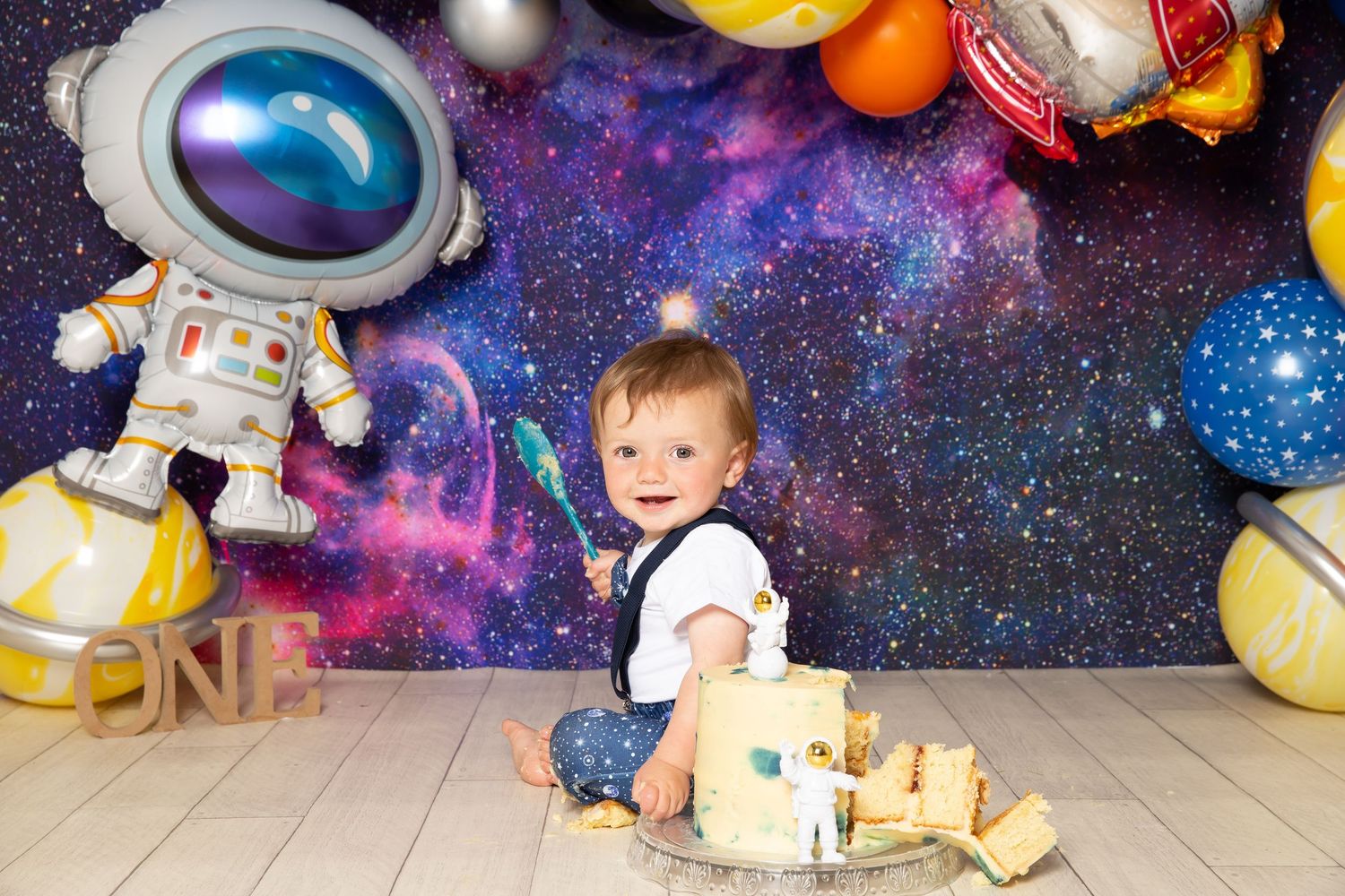 Colorful space-themed birthday party setup with astronaut decorations, planets, and galaxy backdrop for a celebration.