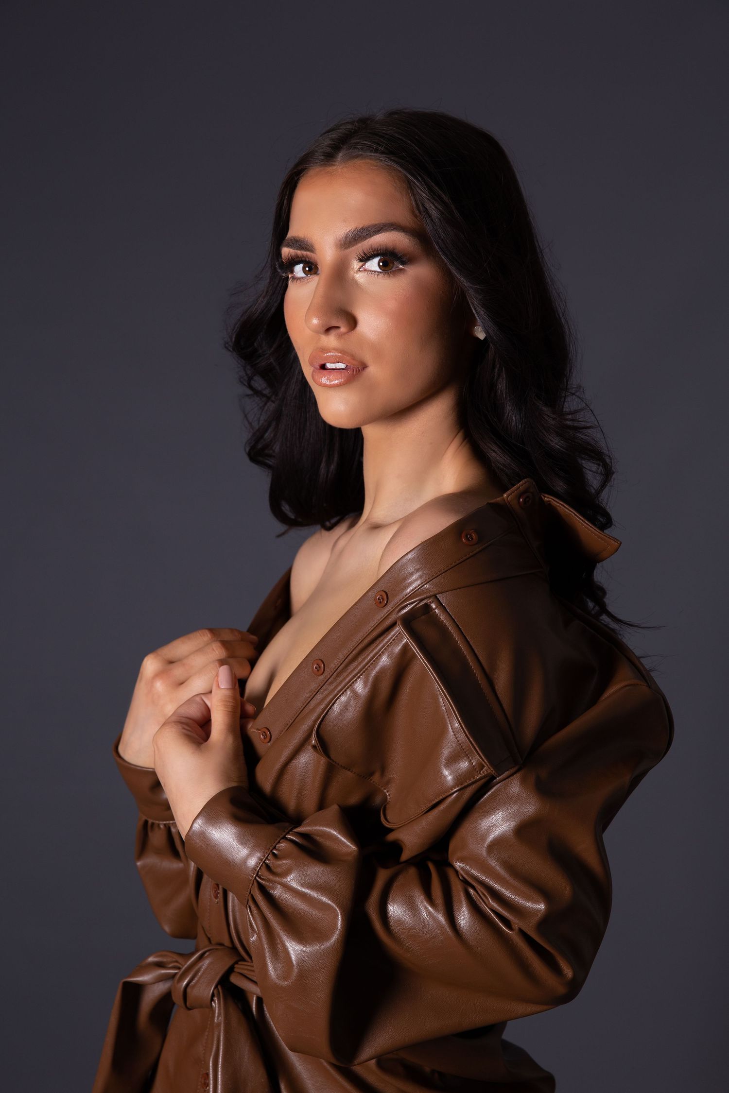 Model poses in brown leather jacket against dark background showing different angles in fashion photoshoot series.