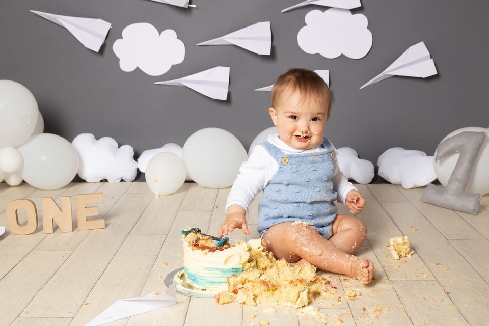 Paper airplanes and white cloud decorations create a whimsical backdrop for a baby photoshoot setting.