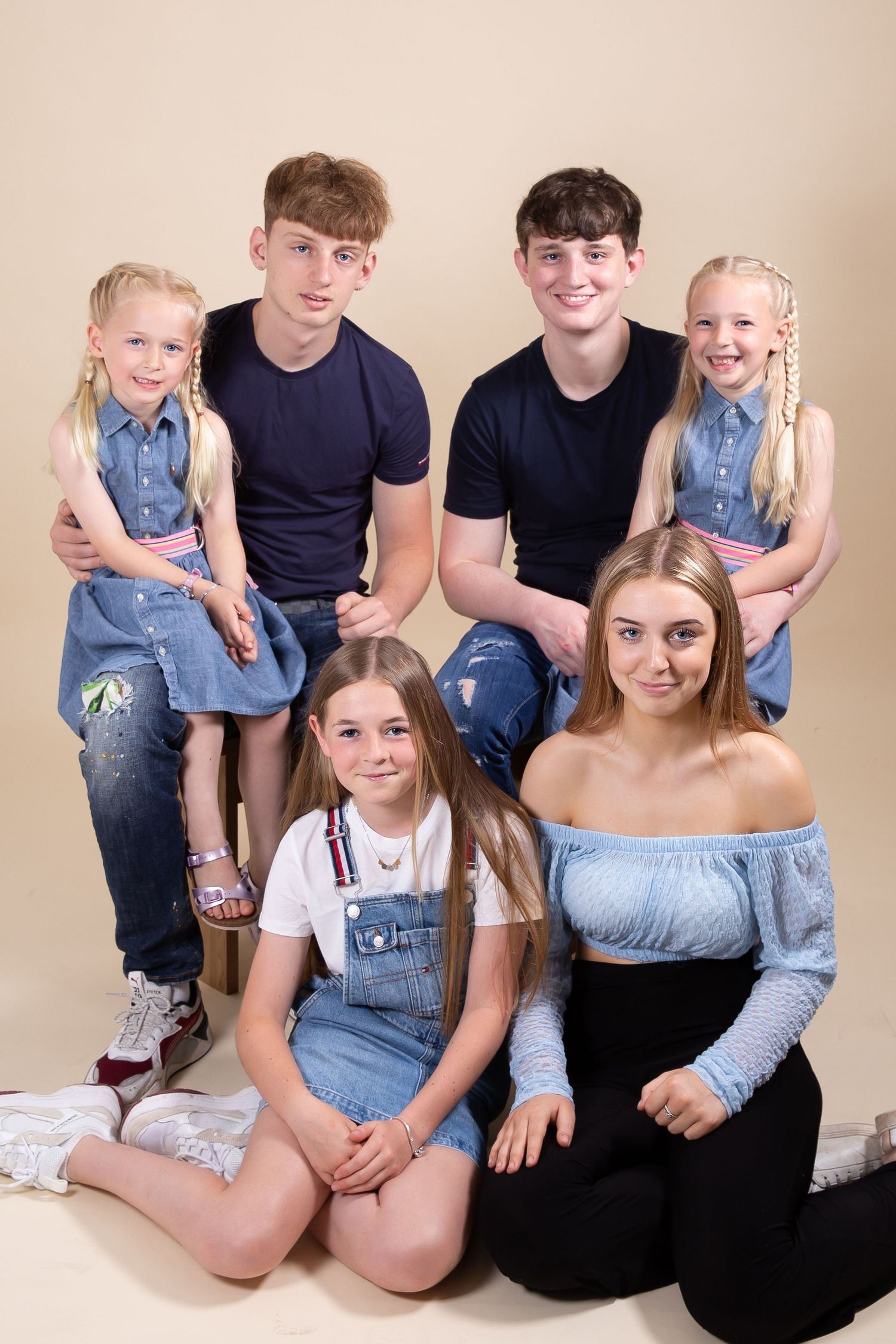 Family group portrait wearing coordinated denim and casual attire posed against neutral background.
