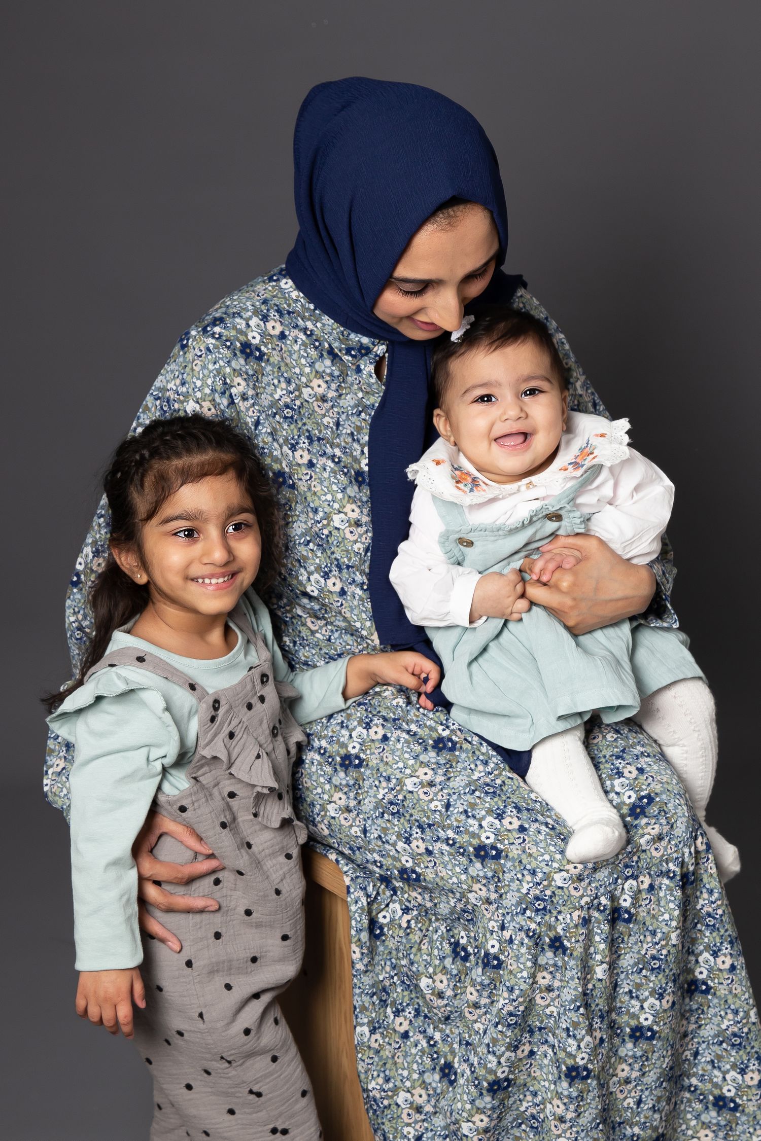 A series of studio portraits showing joyful moments between siblings in coordinated gray and blue outfits.
