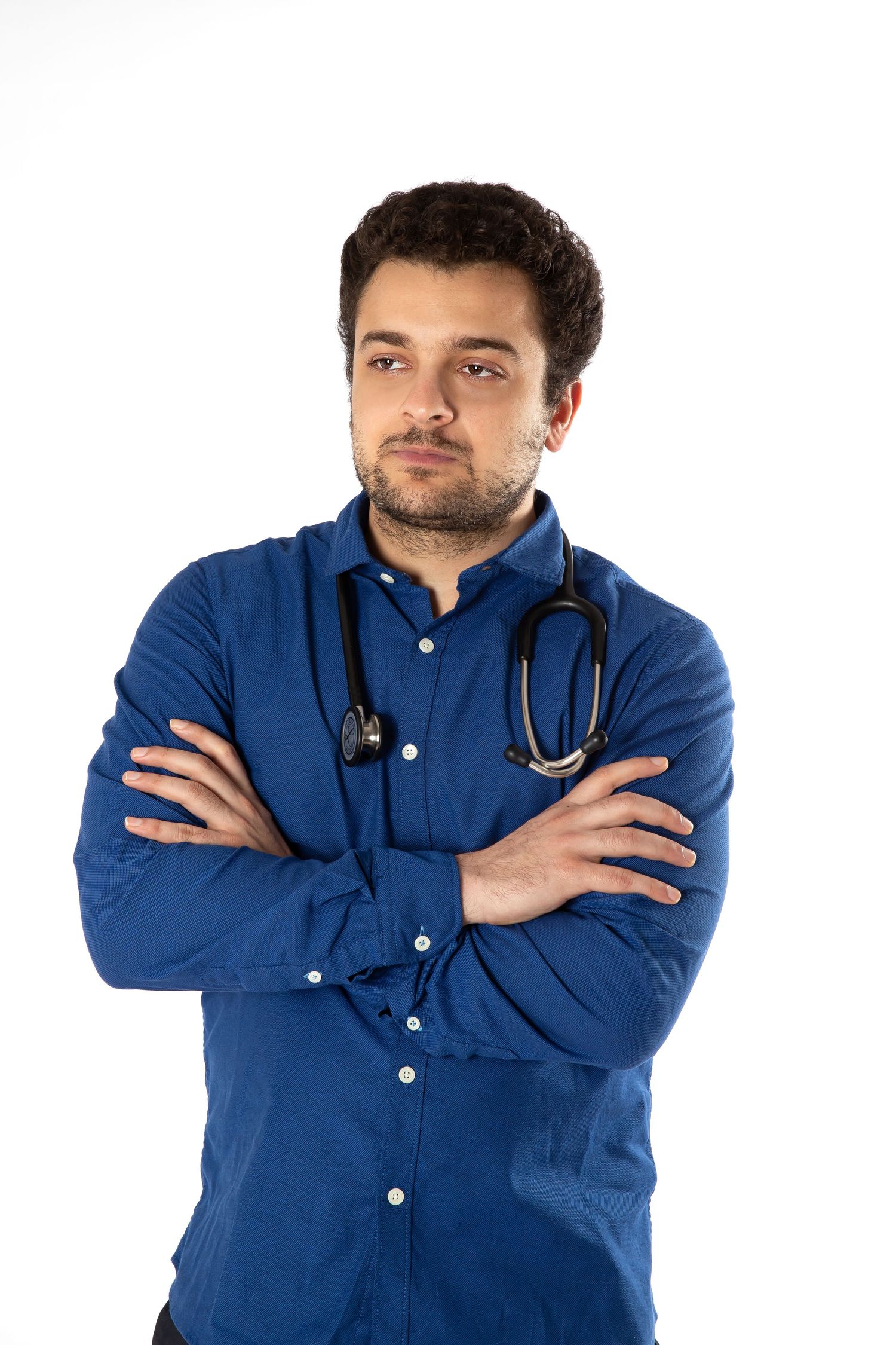 Healthcare professional wearing a blue button-down shirt and stethoscope stands with arms crossed and confident posture.