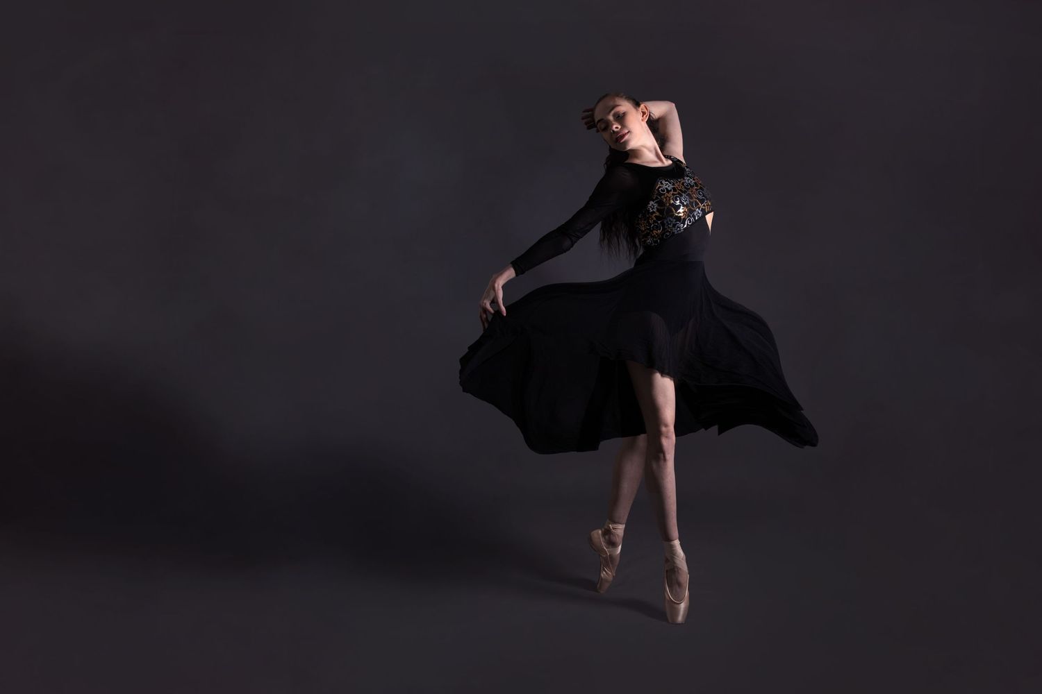 A sequence of ballet dancers mid-leap performing graceful airborne dance movements in dramatic lighting.