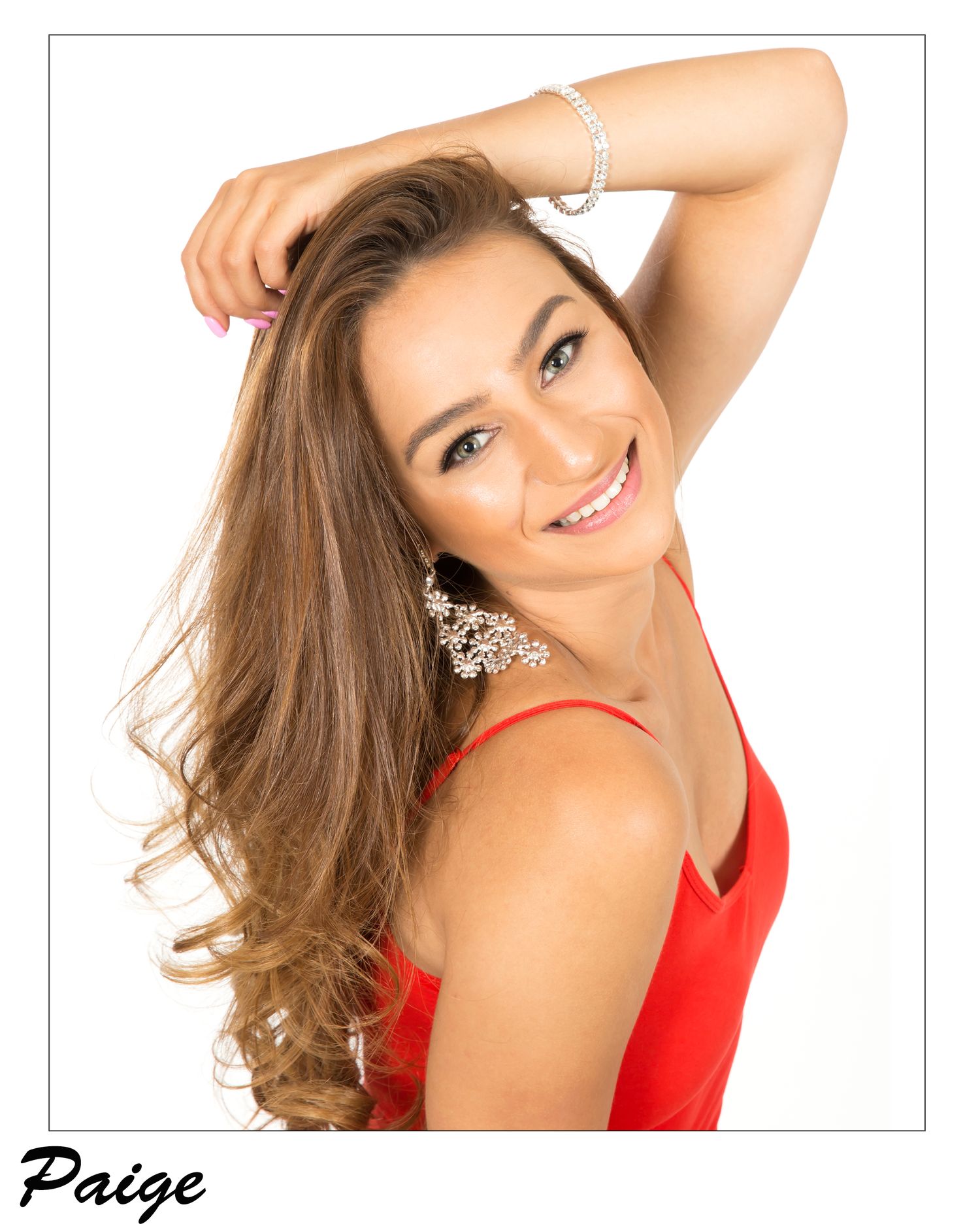 Portrait photo of a person with wavy brown hair wearing a red sleeveless top and posing against a white background.