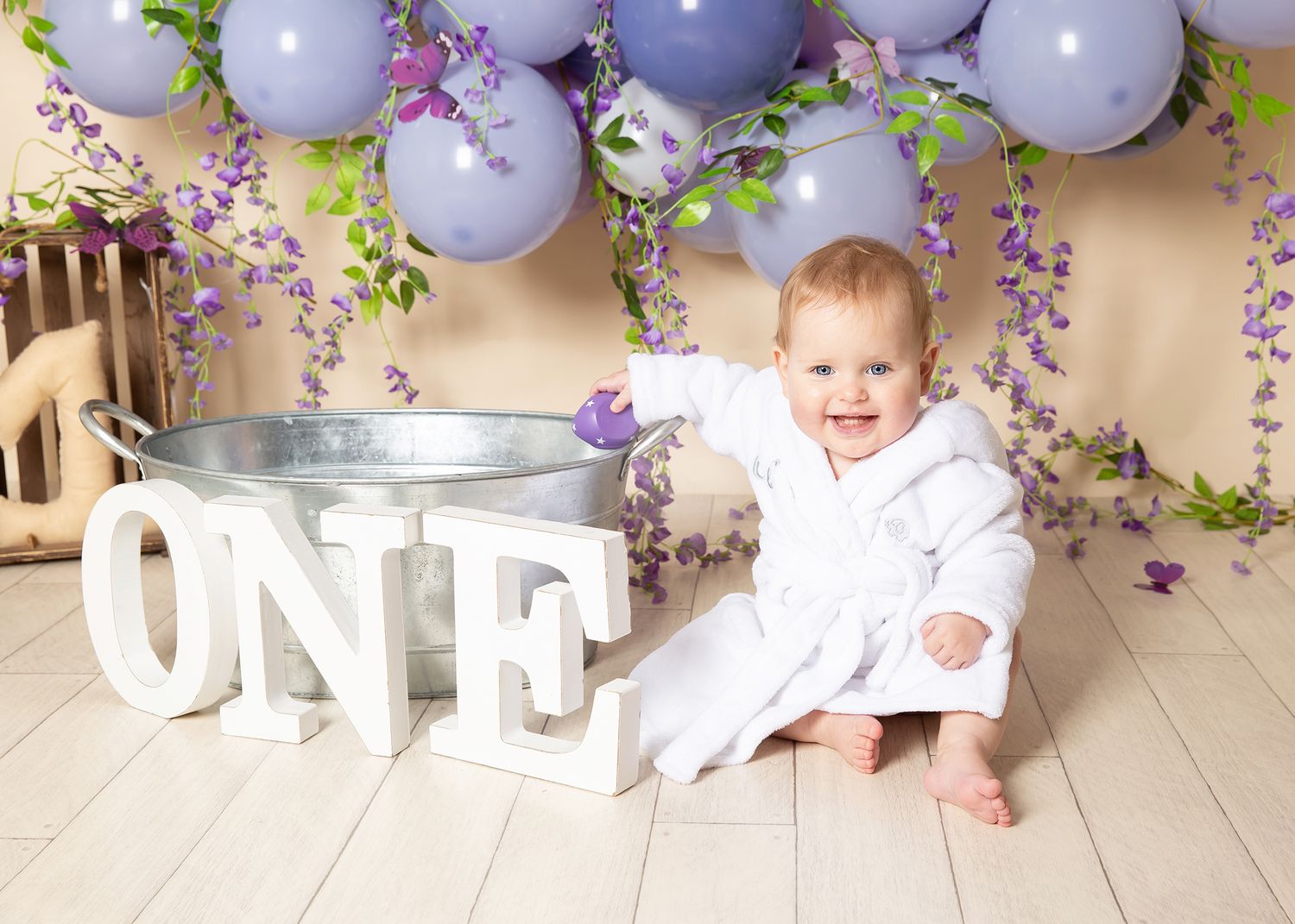 First birthday celebration setup with lavender balloons, floral decor and white 
