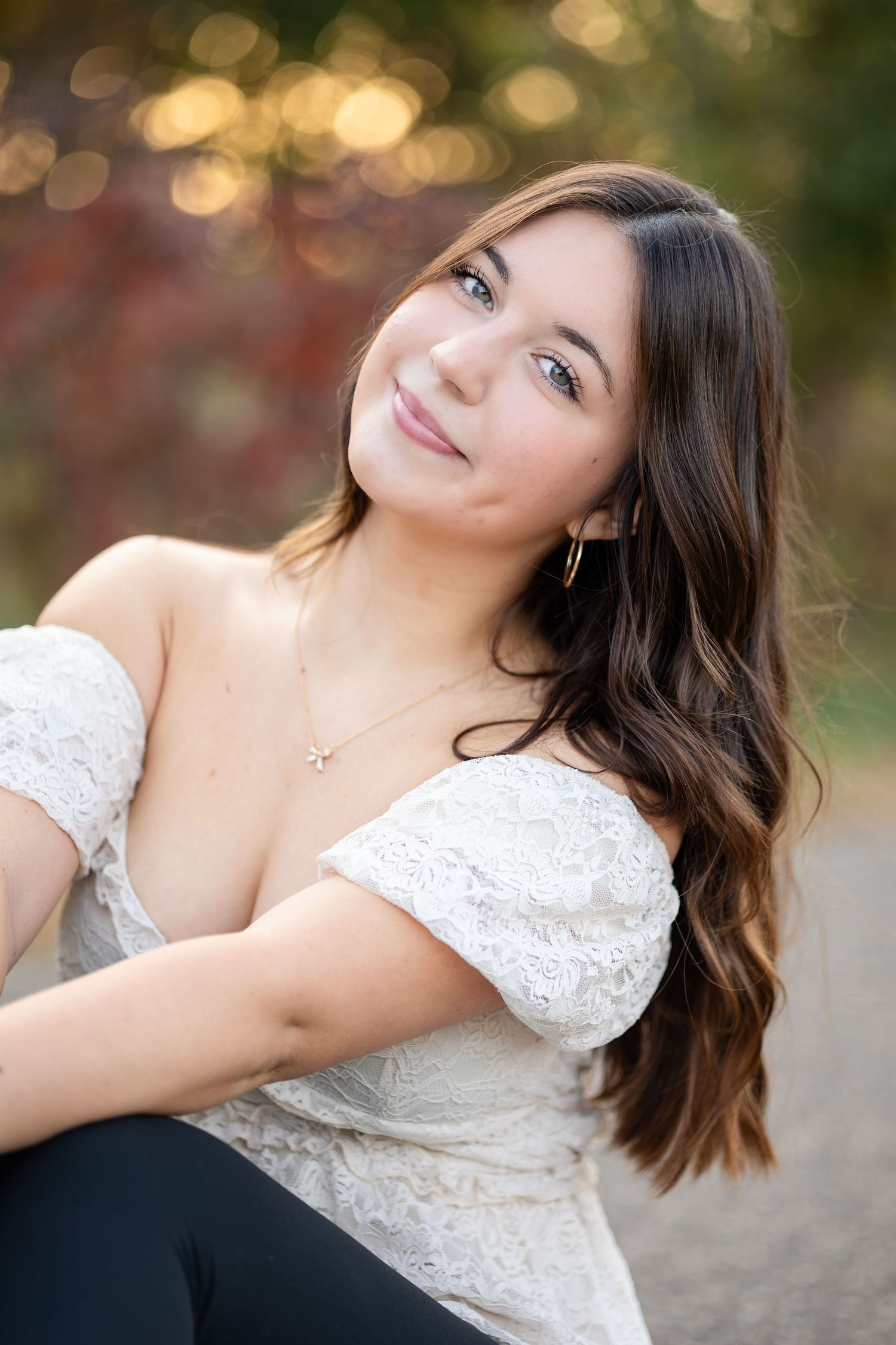 Outdoor portrait with bokeh background wearing white lace top.