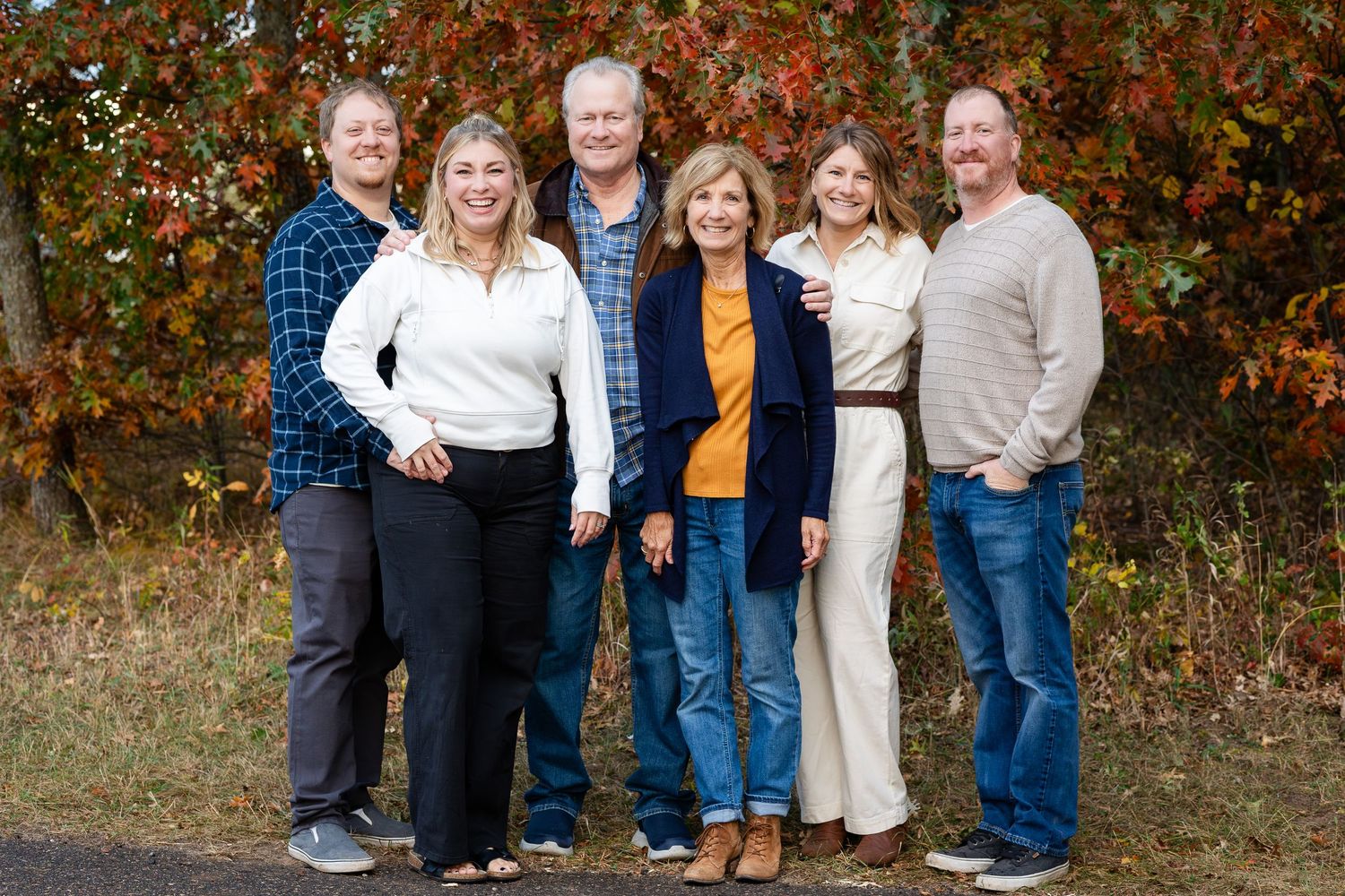 Family group photo against vibrant fall foliage background.