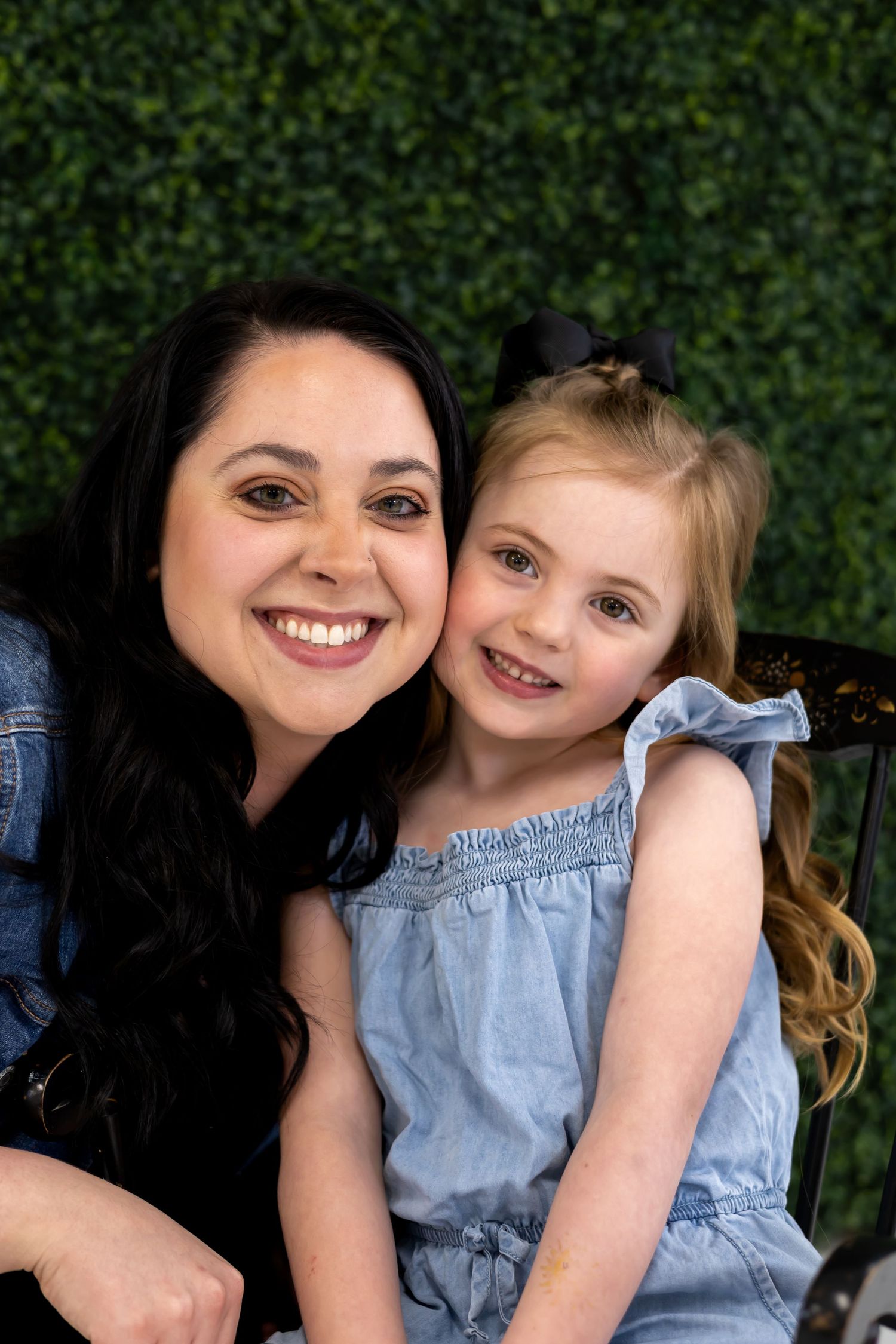 A heartwarming outdoor portrait against a green hedge background on a sunny day.
