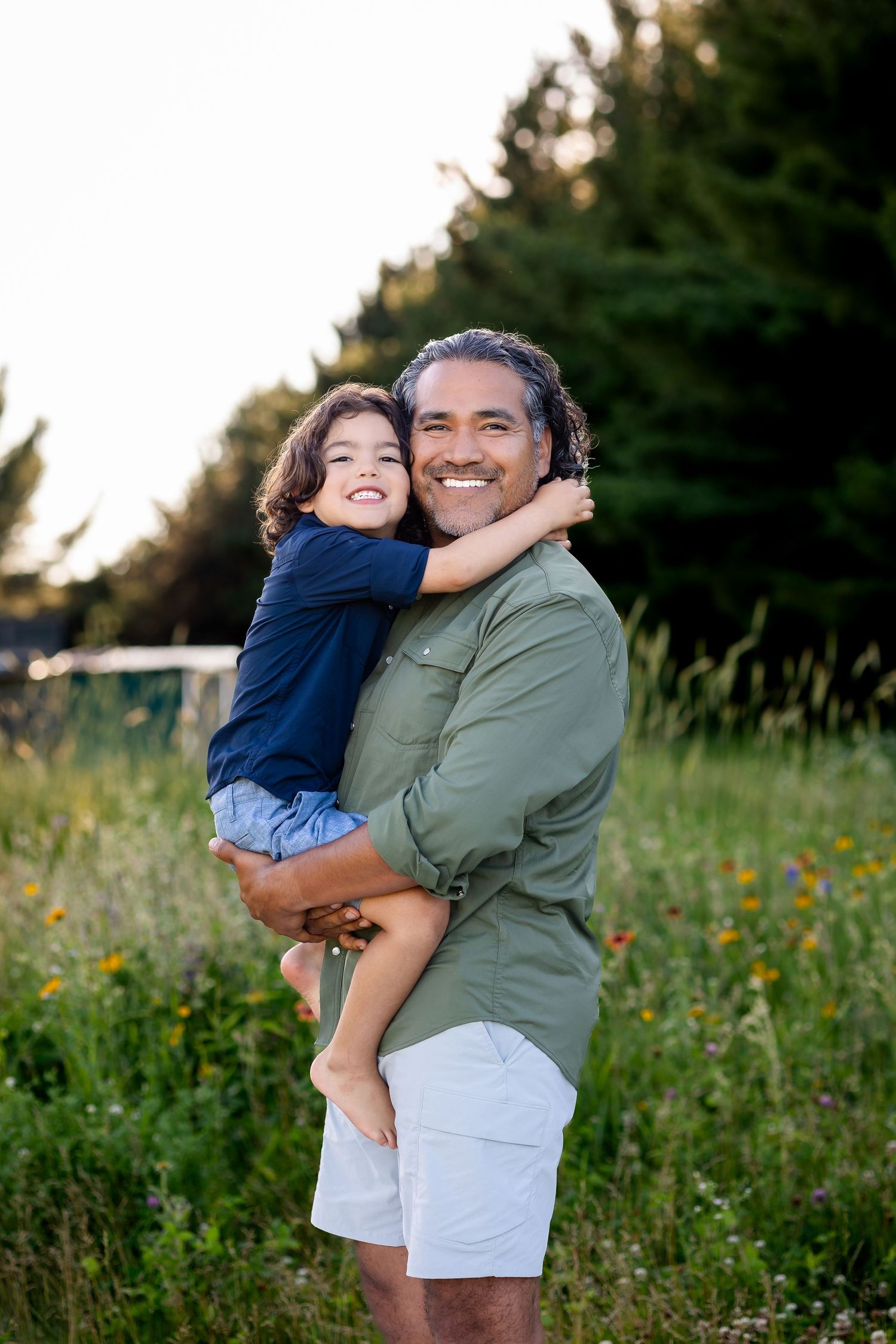 A parent and child share joyful moments together while playing in a wildflower meadow at sunset.