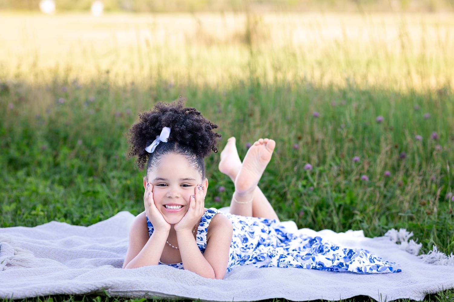 People lying down in a grassy field during a sunny outdoor photo session.