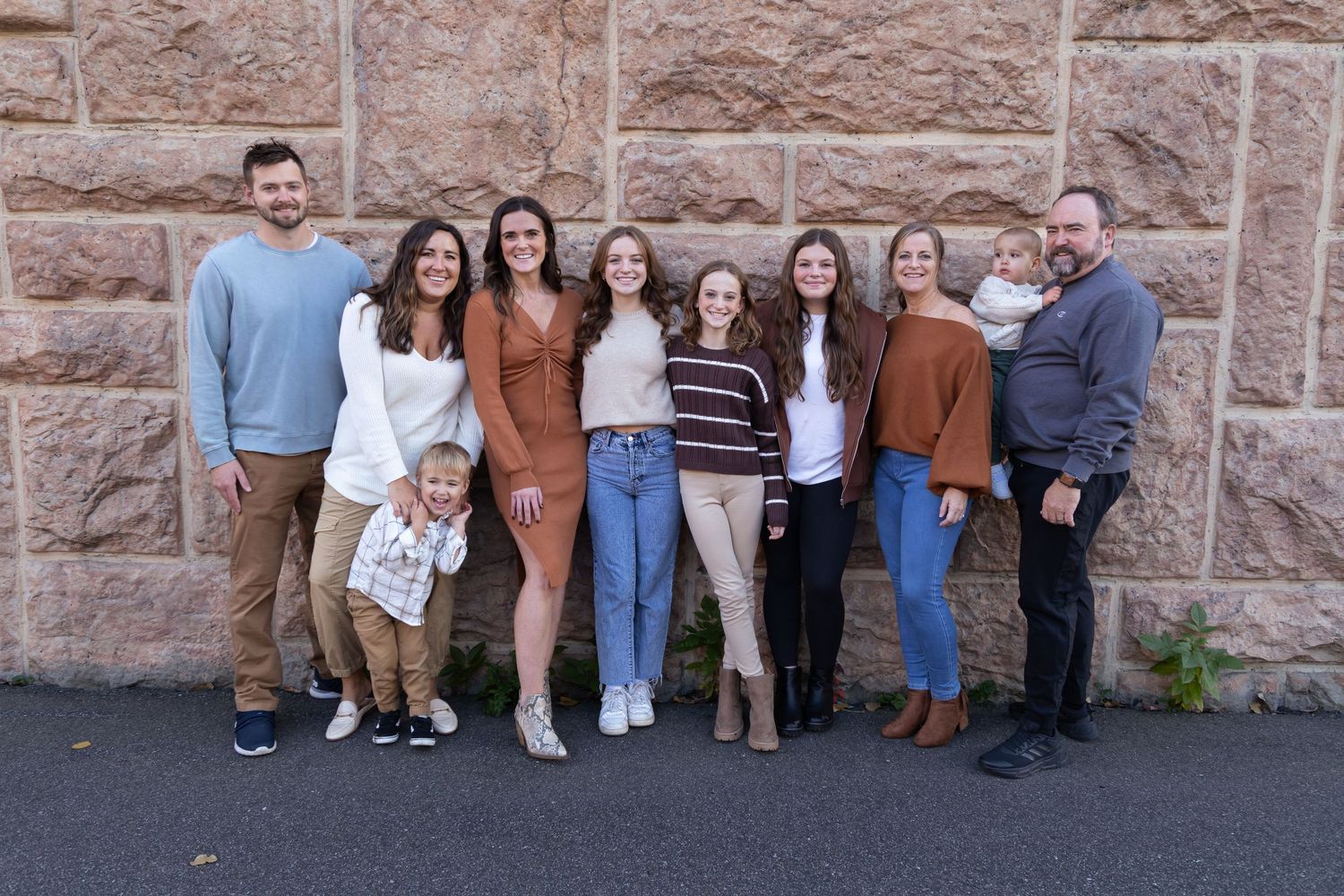 People lined up against a rustic stone wall wearing coordinated casual outfits.